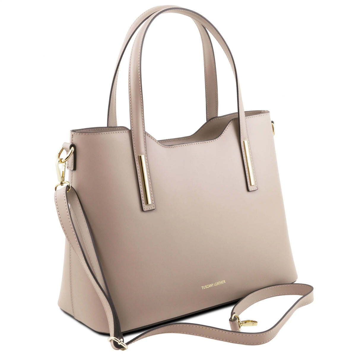 A light taupe leather handbag, featuring dual top handles, a detachable shoulder strap, and gold-tone hardware accents on a white background.