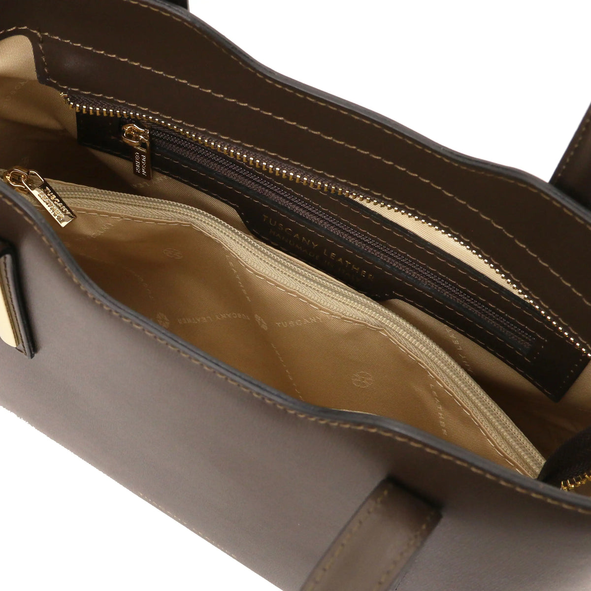 Interior view of a dark chocolate handbag with visible stitching, zippered pocket and beige lining.