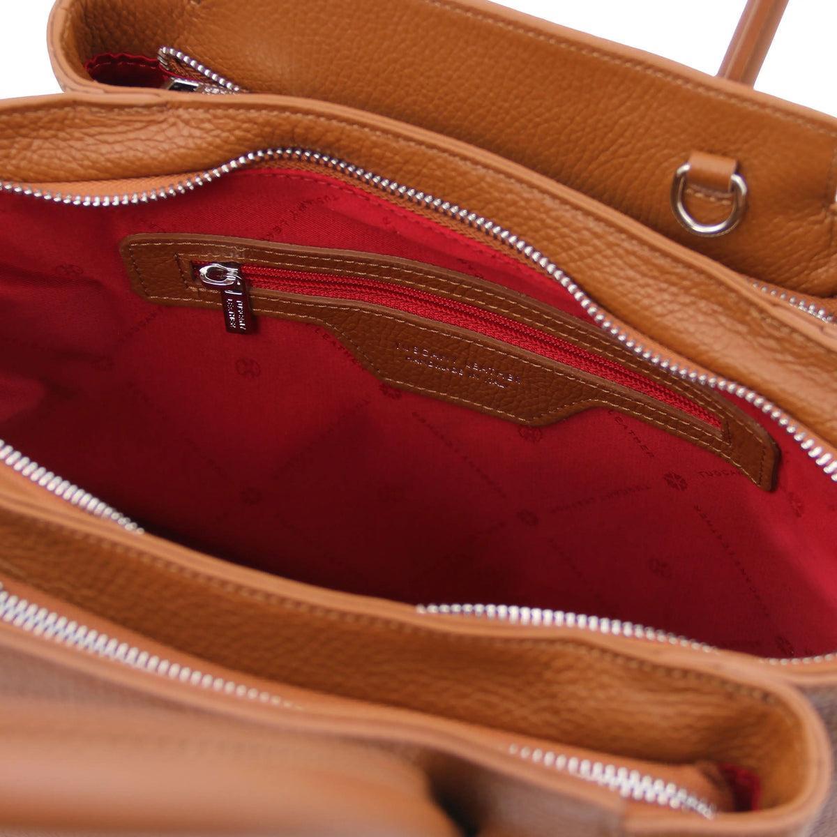 Cognac leather handbag with a red interior lining, zip pocket and visible brand logo.