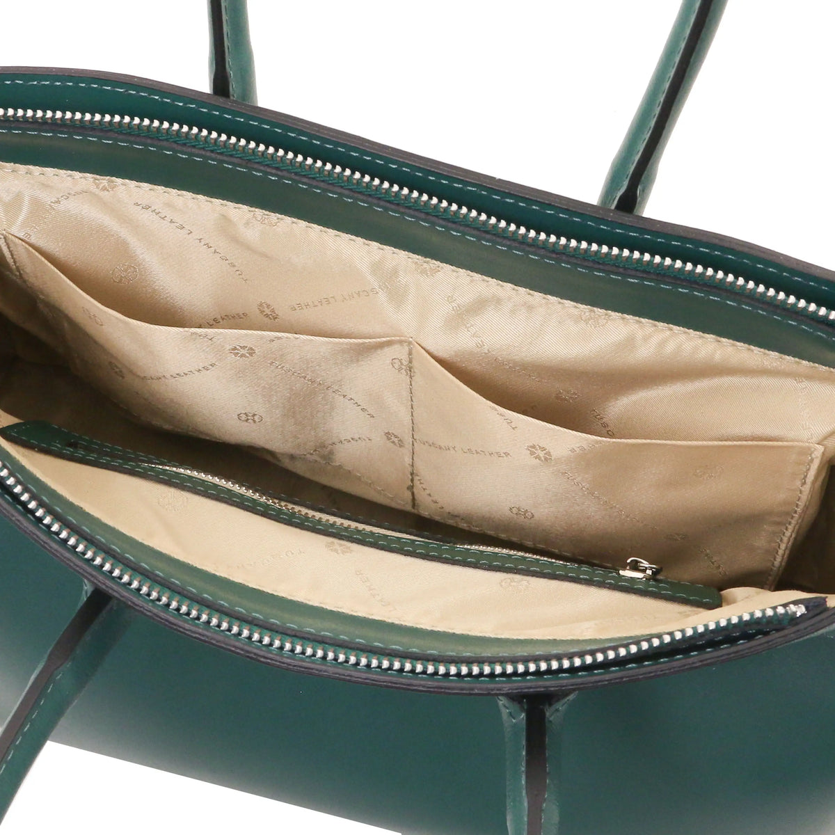 Close-up of the interior of a structured handbag in teal leather, showing a beige patterned fabric lining with two opened pockets and silver-tone zippers.