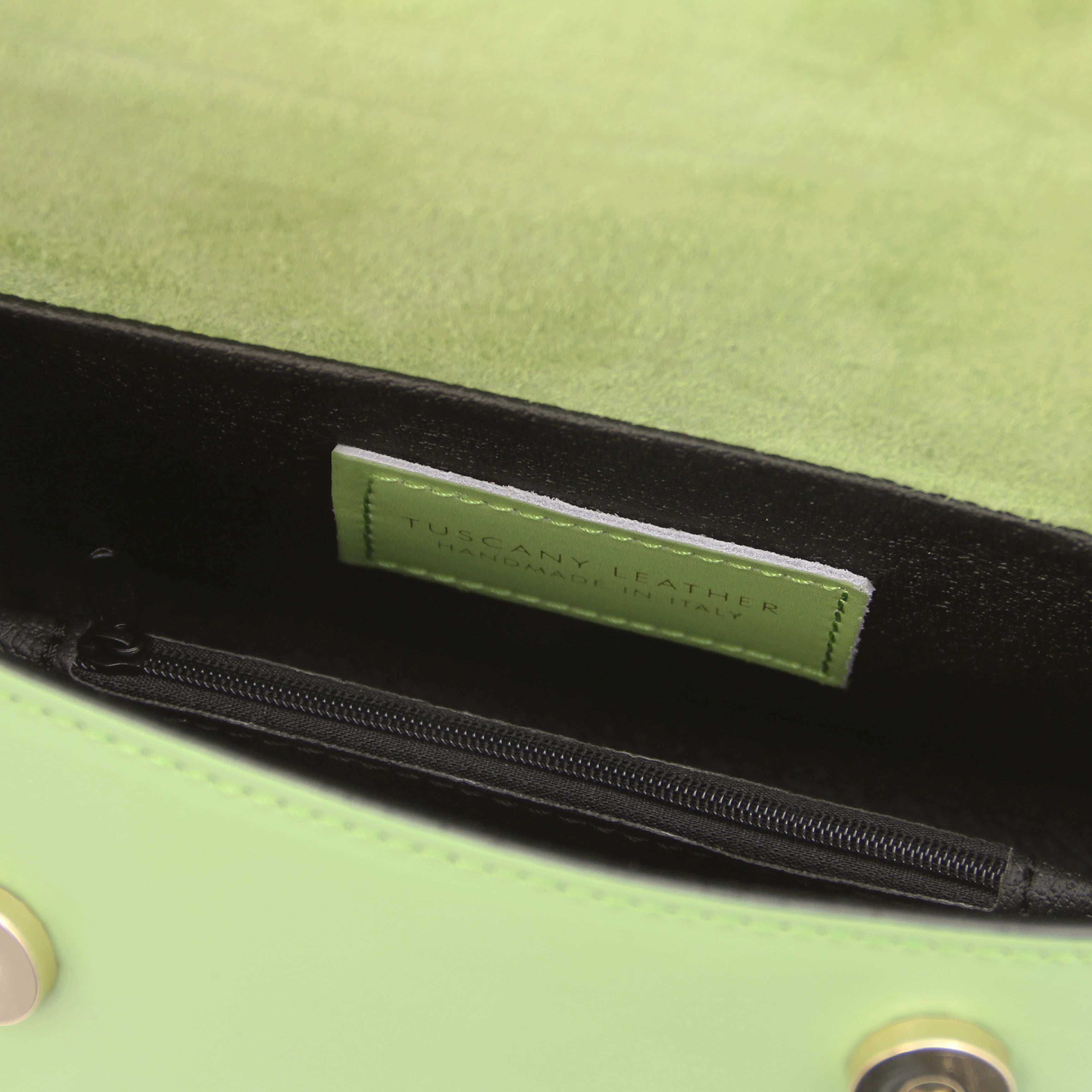 Interior zip pocket view TL Leather Assymetrical Shoulder Bag in Green showing magnetic button closures and Tuscany Leather branding