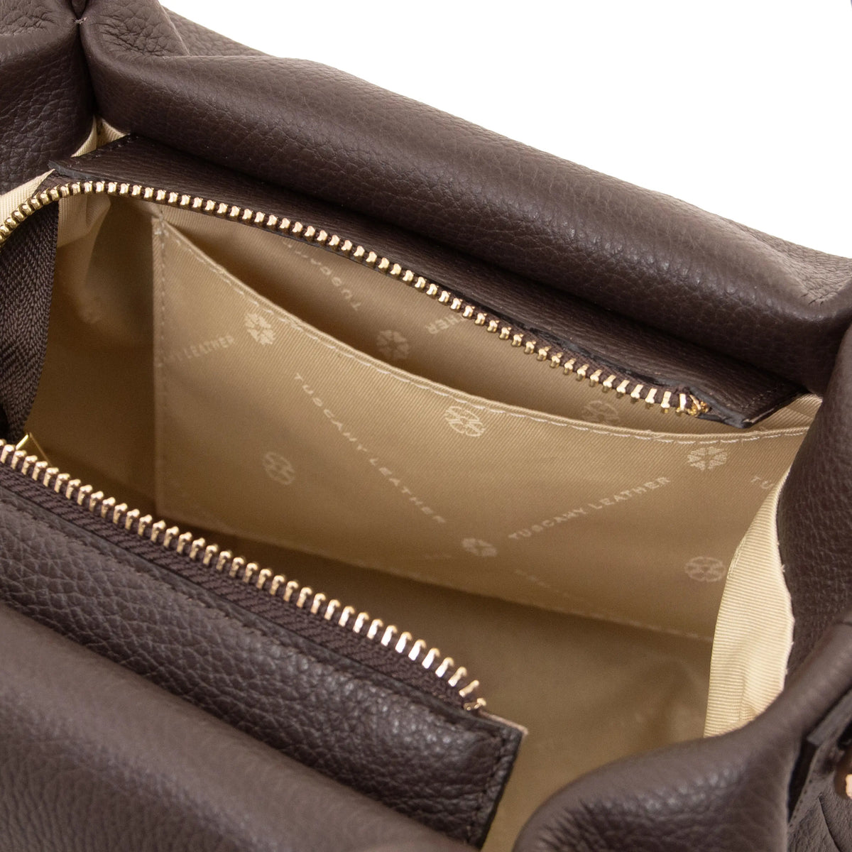 Close-up of a Chocolate textured leather handbag interior showing a beige patterned lining and gold-tone zipper details.