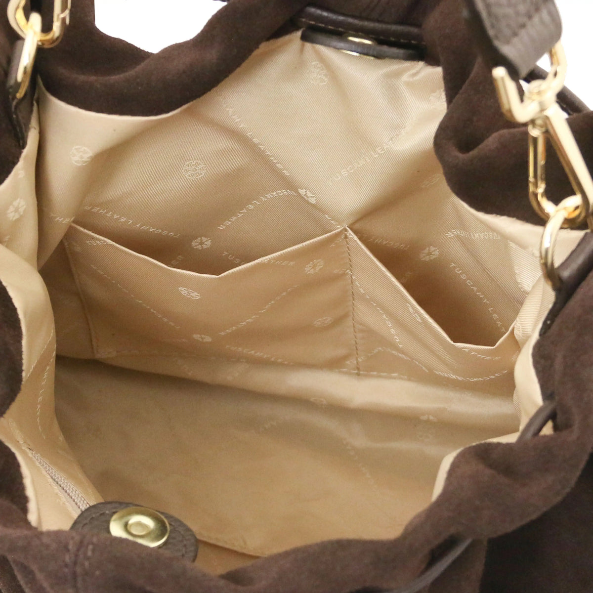 Close-up of the interior of a dark brown suede shoulder bag, showing a beige quilted lining with multiple zippered compartments and gold-tone hardware.