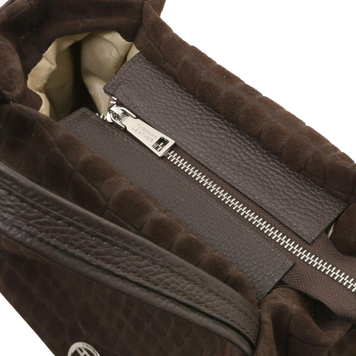 Close-up of a chocolate textured handbag interior showing a zippered compartment, silver zipper pulls, and a red lining.