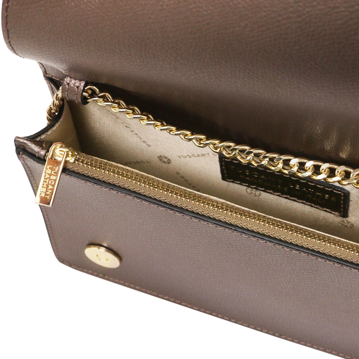Close-up of a bronze textured leather clutch with a gold-tone chain strap and zipper, showing the interior lining and a visible brand patch.