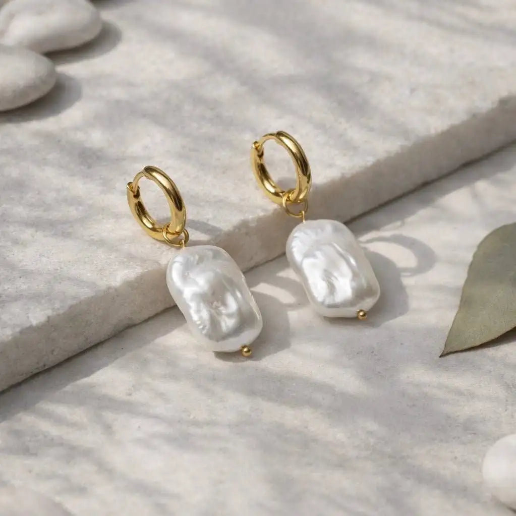 Amalfi Aurora 2-in-1 Hoop Earrings are laying on white stone in the shade