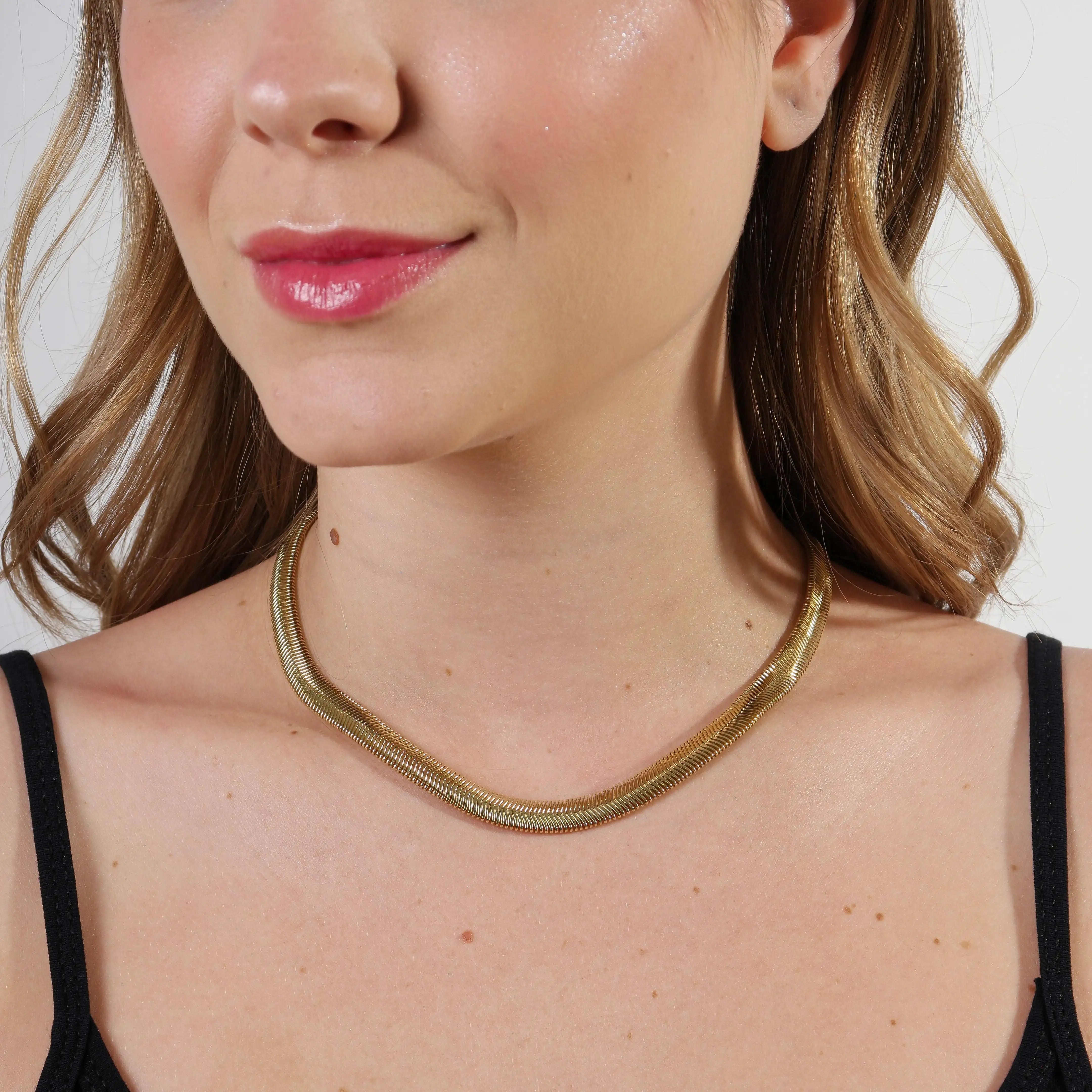 Woman wearing a16" gold necklace against a neutral background