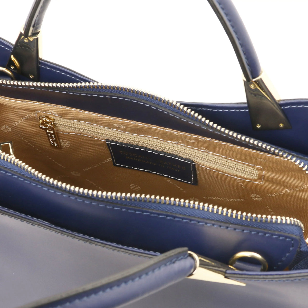 Close-up of a dark blue leather handbag interior with a gold-toned zipper, tan lining, and a visible Balenciaga logo patch on the inside label.