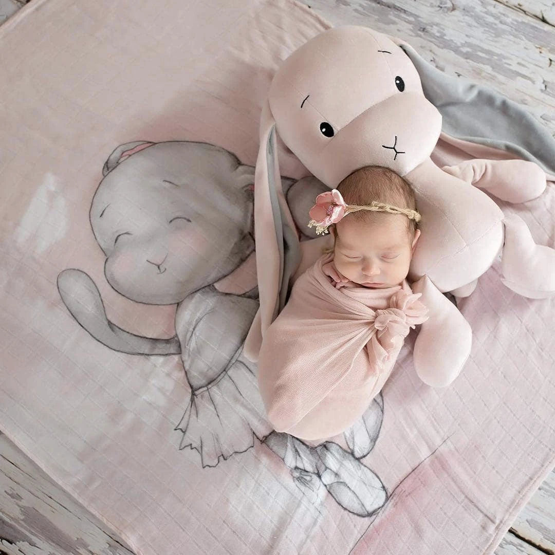 Image of a baby laying on a pink blanket with Effik the pink bunny