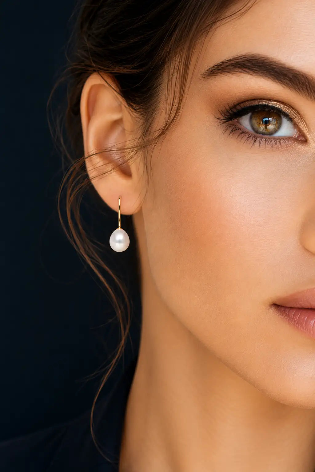 Close-up of a woman wearing pearl earrings with a dark background