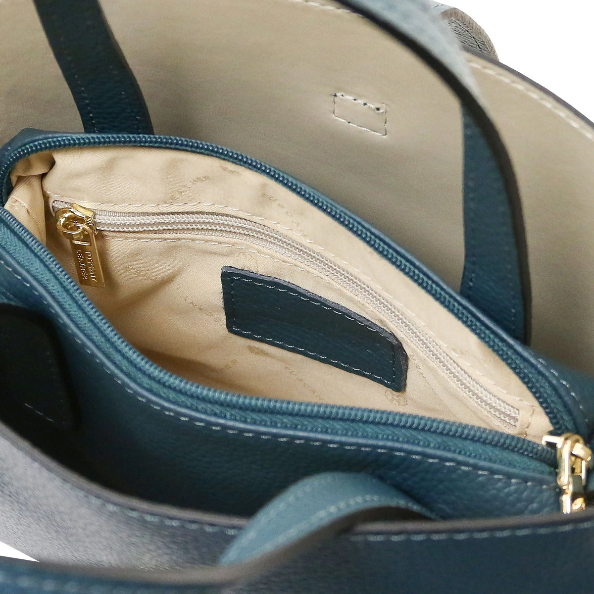 Interior beige lining view Agatha Leather Handbag in teal showing un zipped central compartment