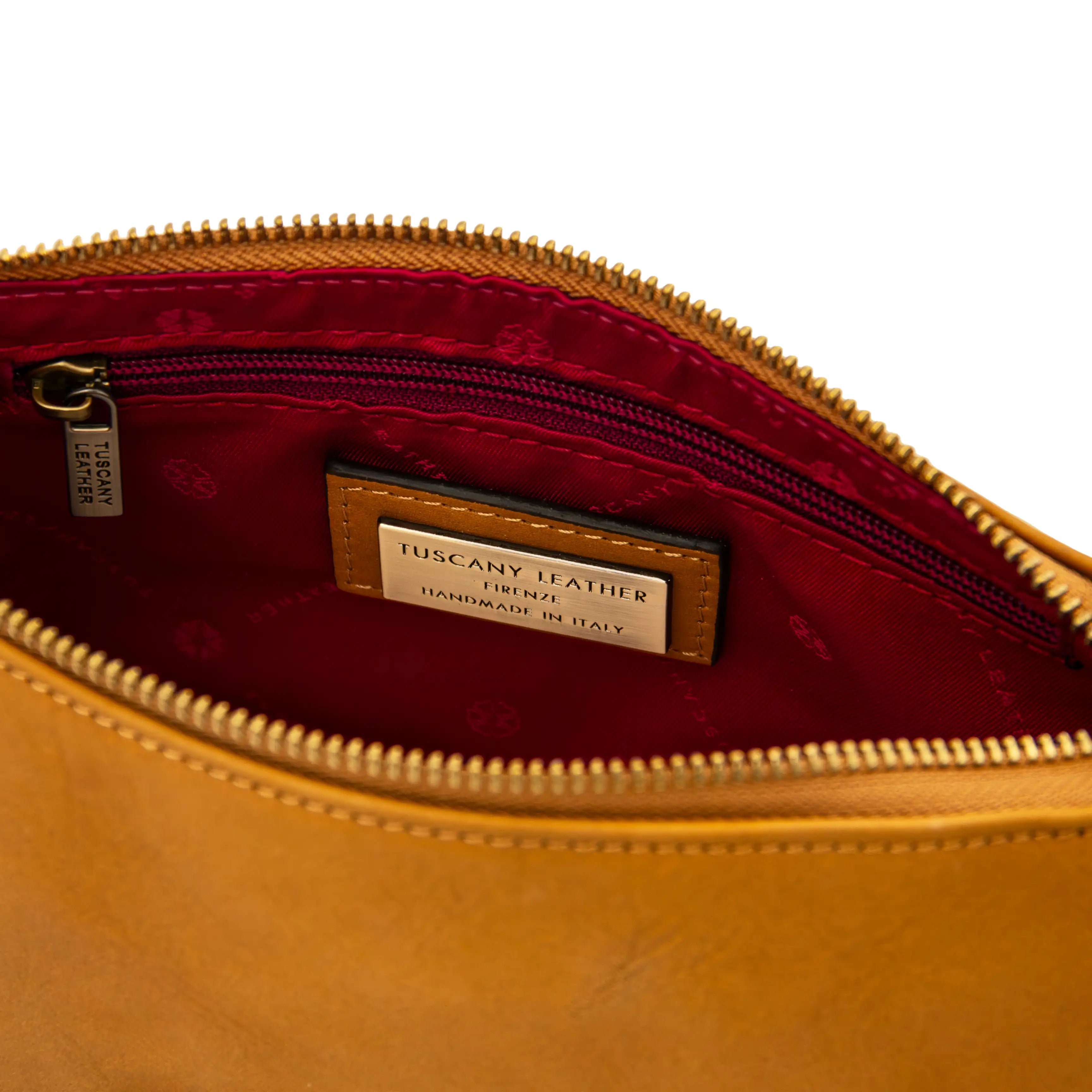 Close-up of interior of a natural leather bag with a visible brand label on a white background on a red lining.