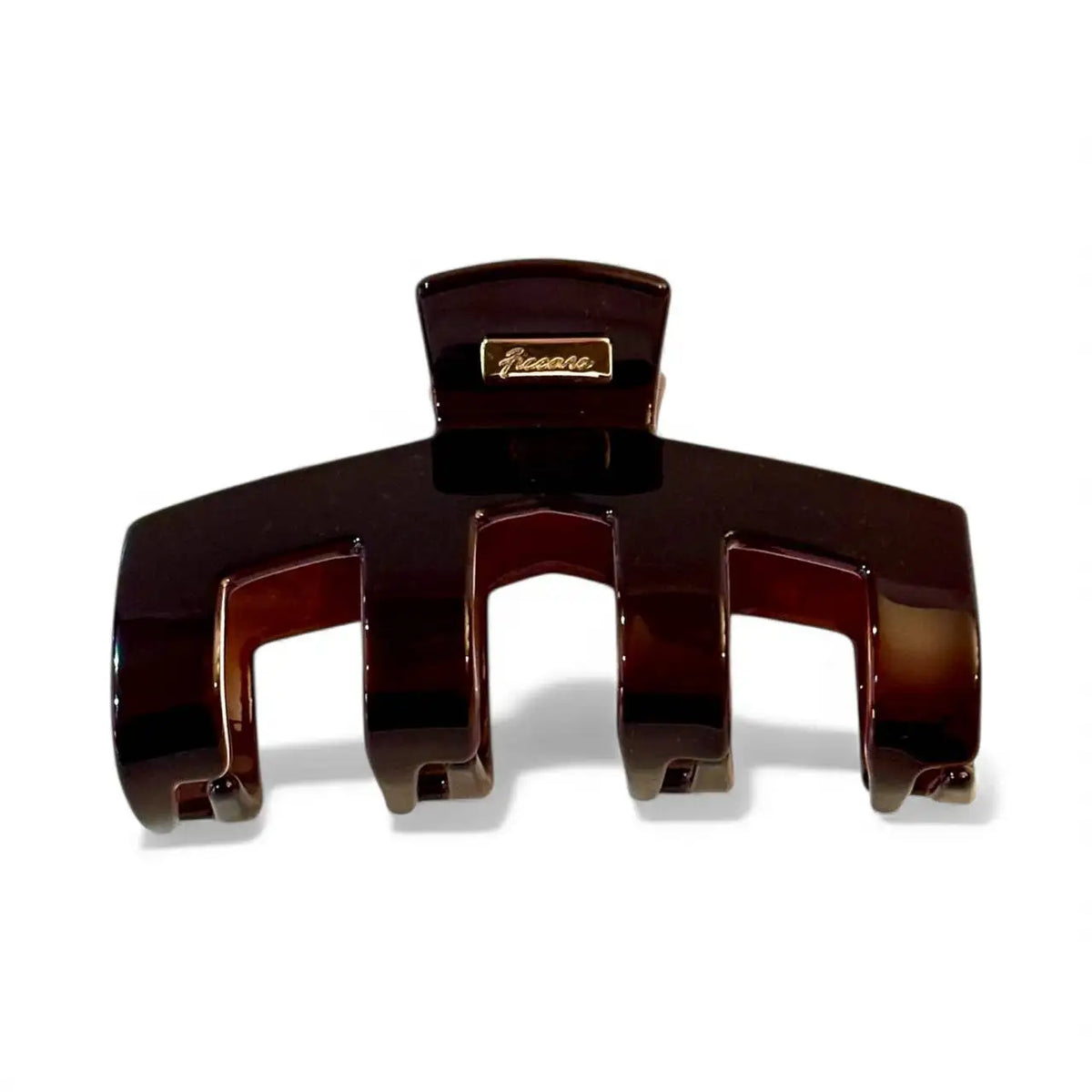 A glossy dark brown hair claw clip with a small gold-tone brand plaque on the top, shown on a clean white background.
