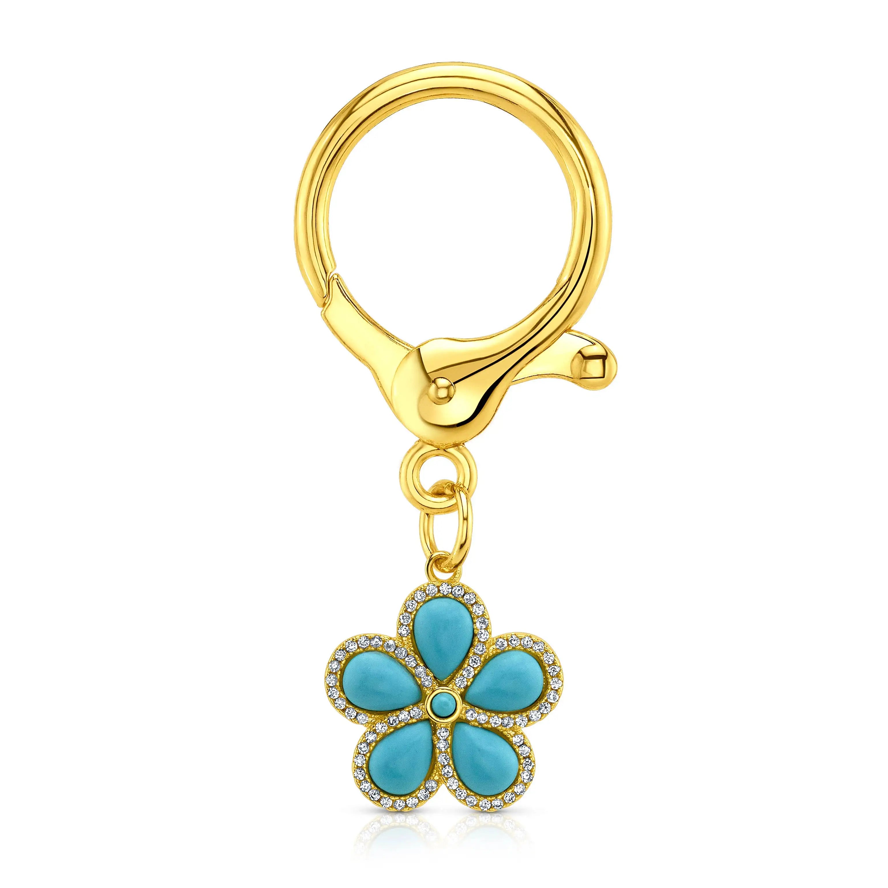 A gold-tone key ring with a dangling flower charm featuring turquoise petals and small clear CZ accents, shown on a clean white background.