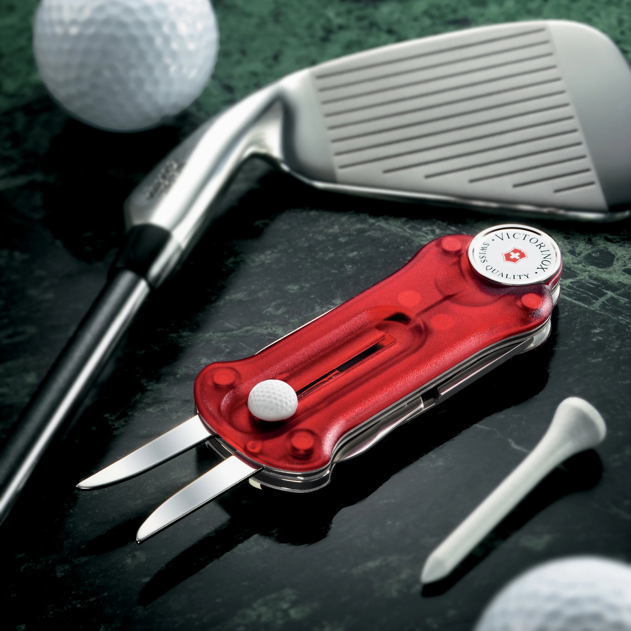 Swiss Army Gold Tool laying next to golfballs, tee and a pitching club