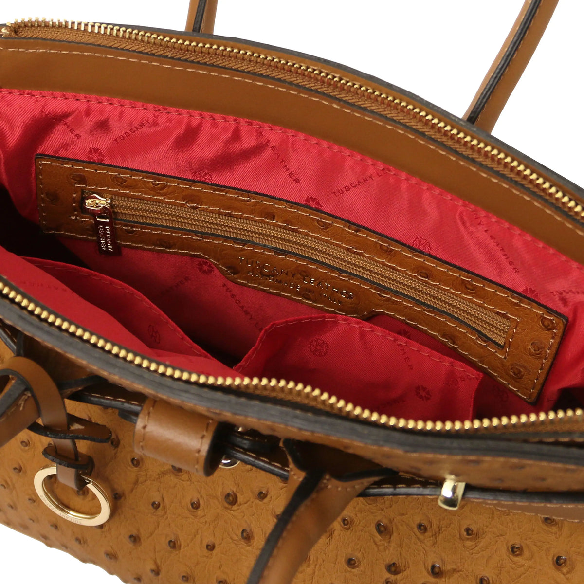 Cognac leather ostrich print handbag with interior zipper pocket and red lining on a white background