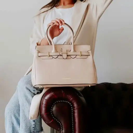 Person holding a beige handbag with a blurred background