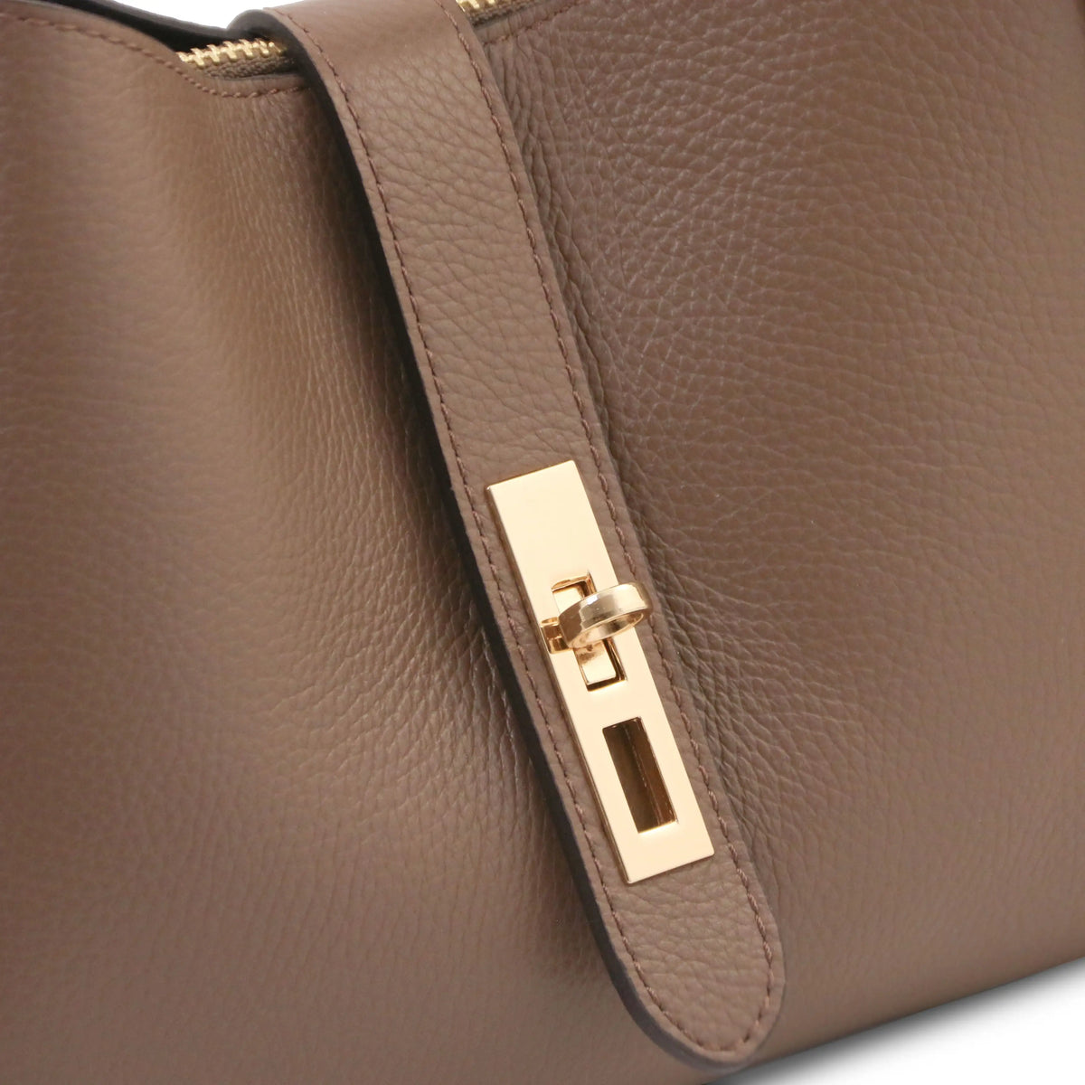 Close-up of a dark taupe pebbled leather handbag featuring a gold-tone metal turn-lock clasp on a matching leather strap.