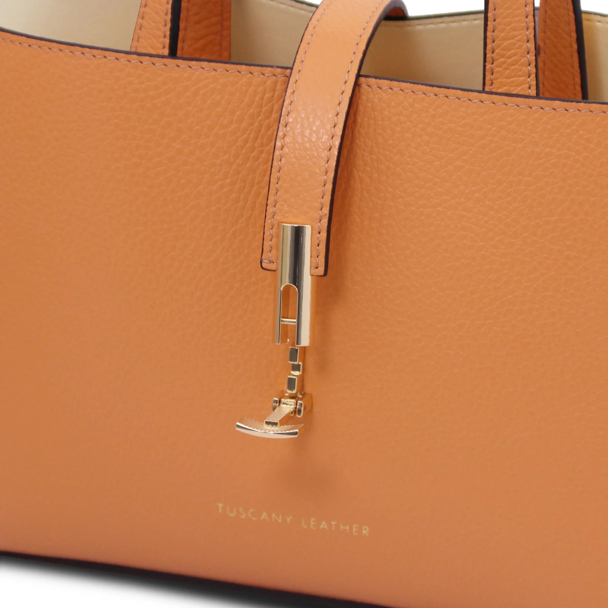 Apricot leather handbag with gold twist clasp lock and 'Tuscany Leather' branding.