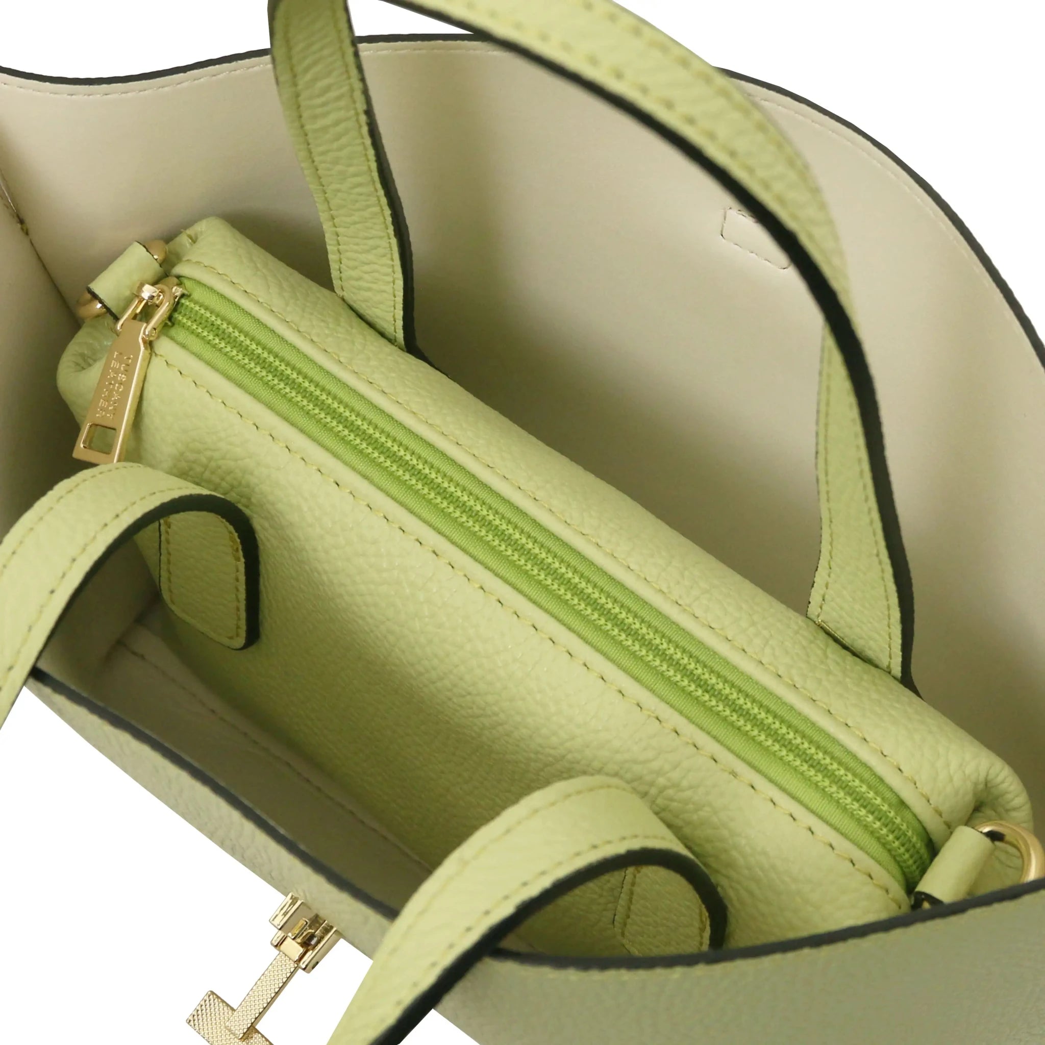Close-up of a beige interior of lime green bag with zip centered compartment and stitching details.