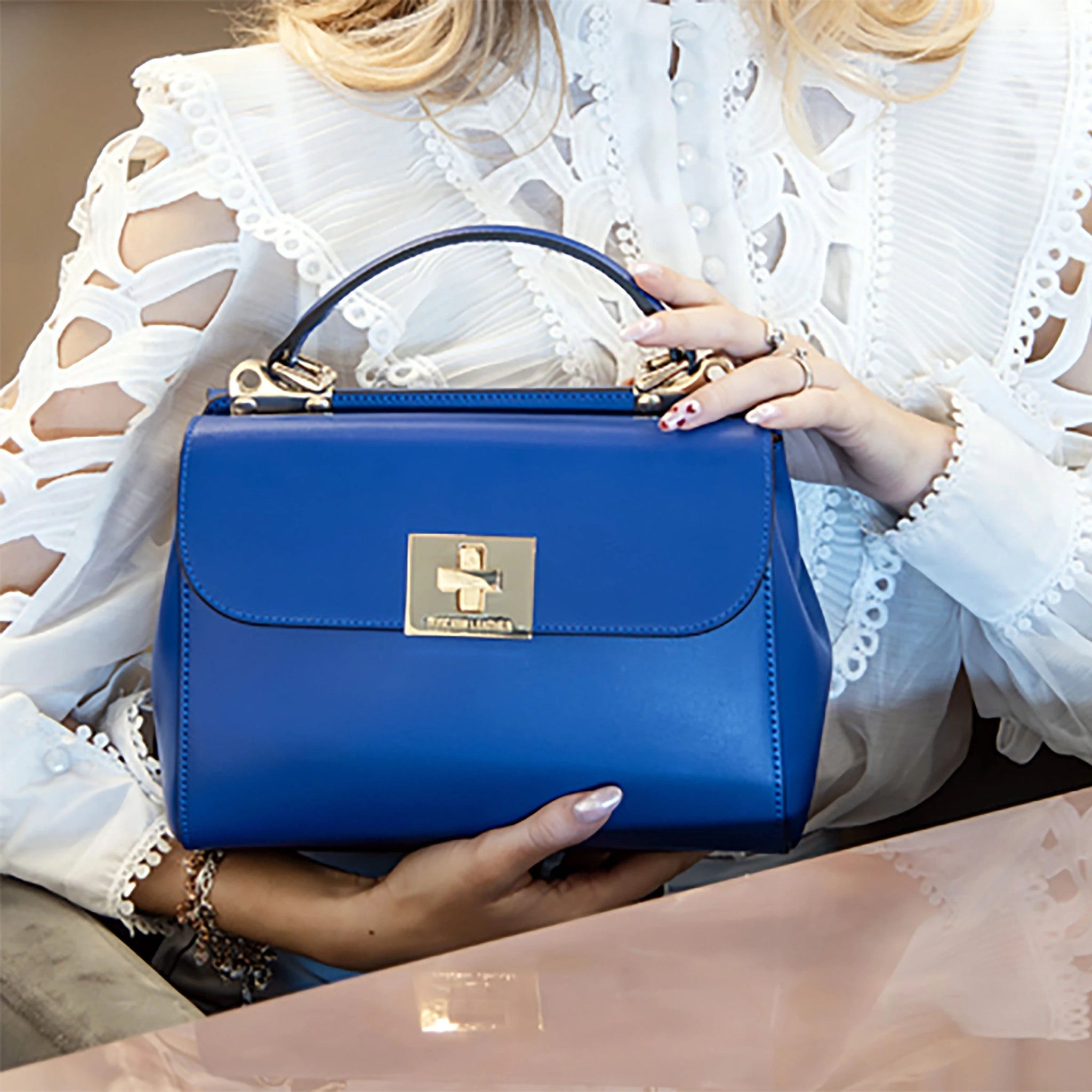 A model wearing white lace shirt with cut out design, holding the Blue Armonia leather bag