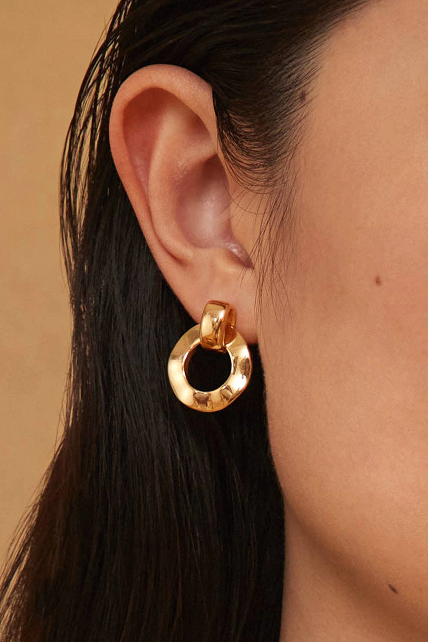 A woman is wearing the Aya Infinity Goldon on her right ear