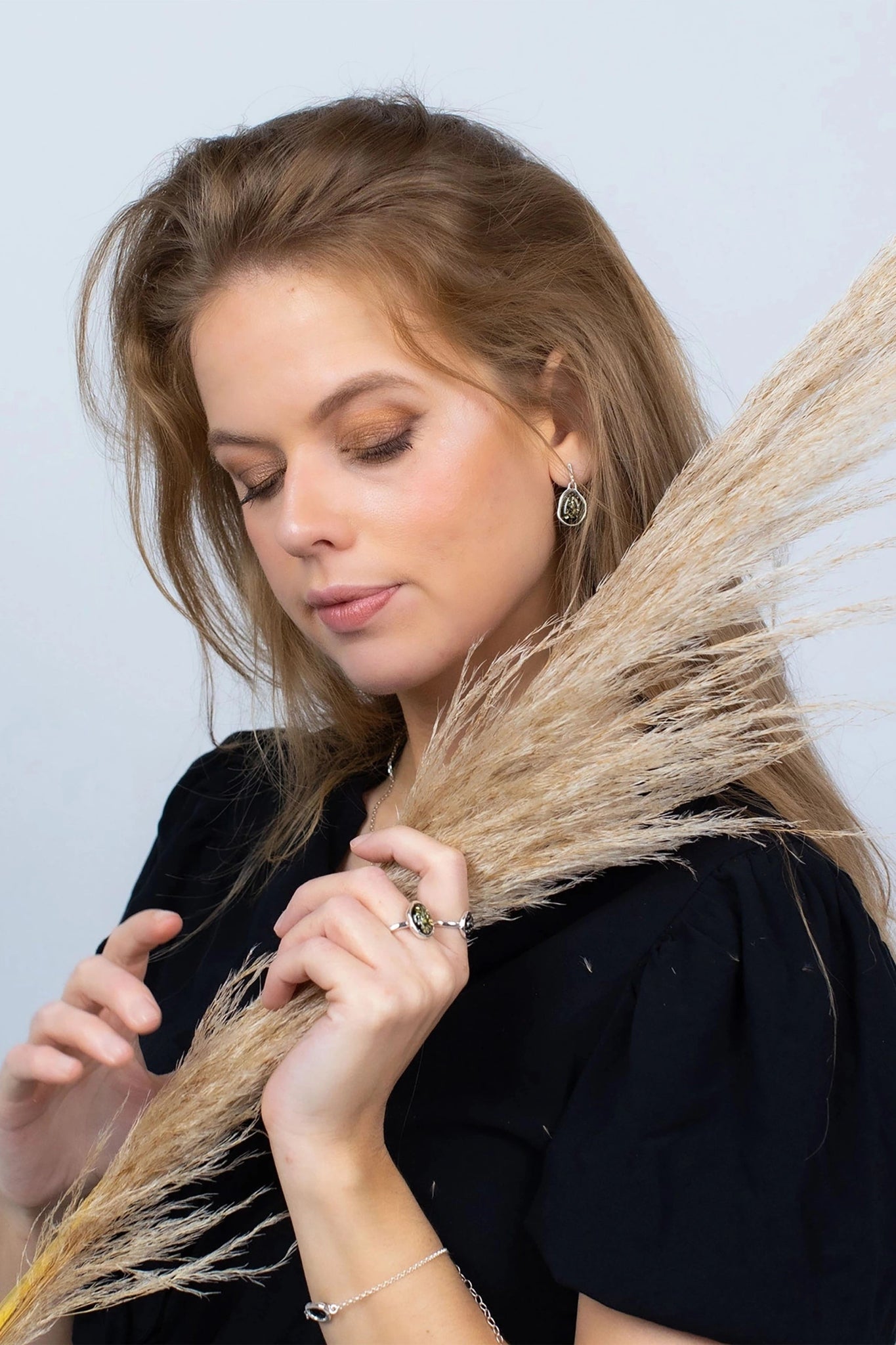 a female model i is wearing the Baltic Green Amber Asymmetrical Sterling Silver Drop Earrings