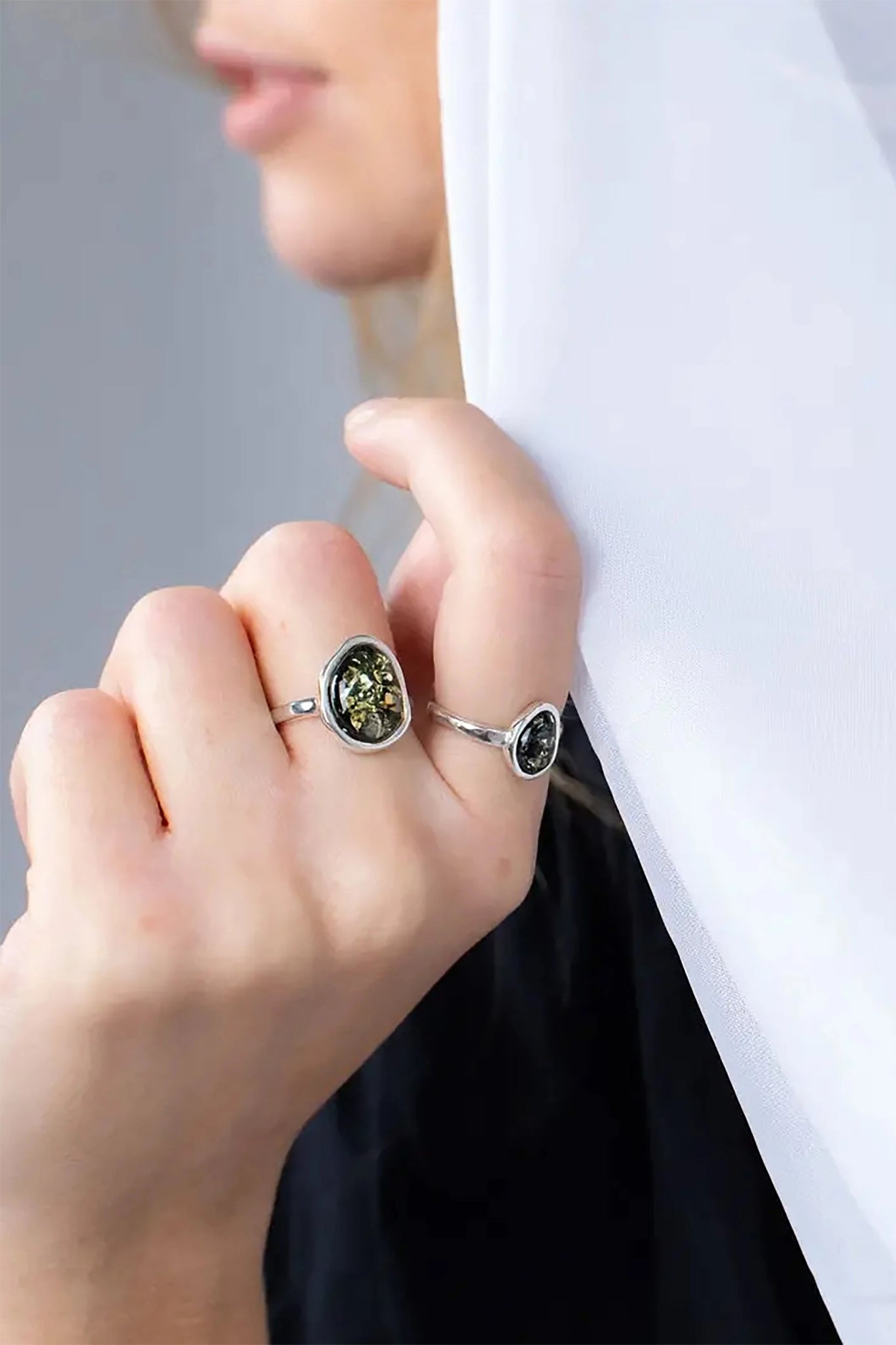 A female model is wearing the Baltic Green Amber Element Solitaire Adjustable Ring