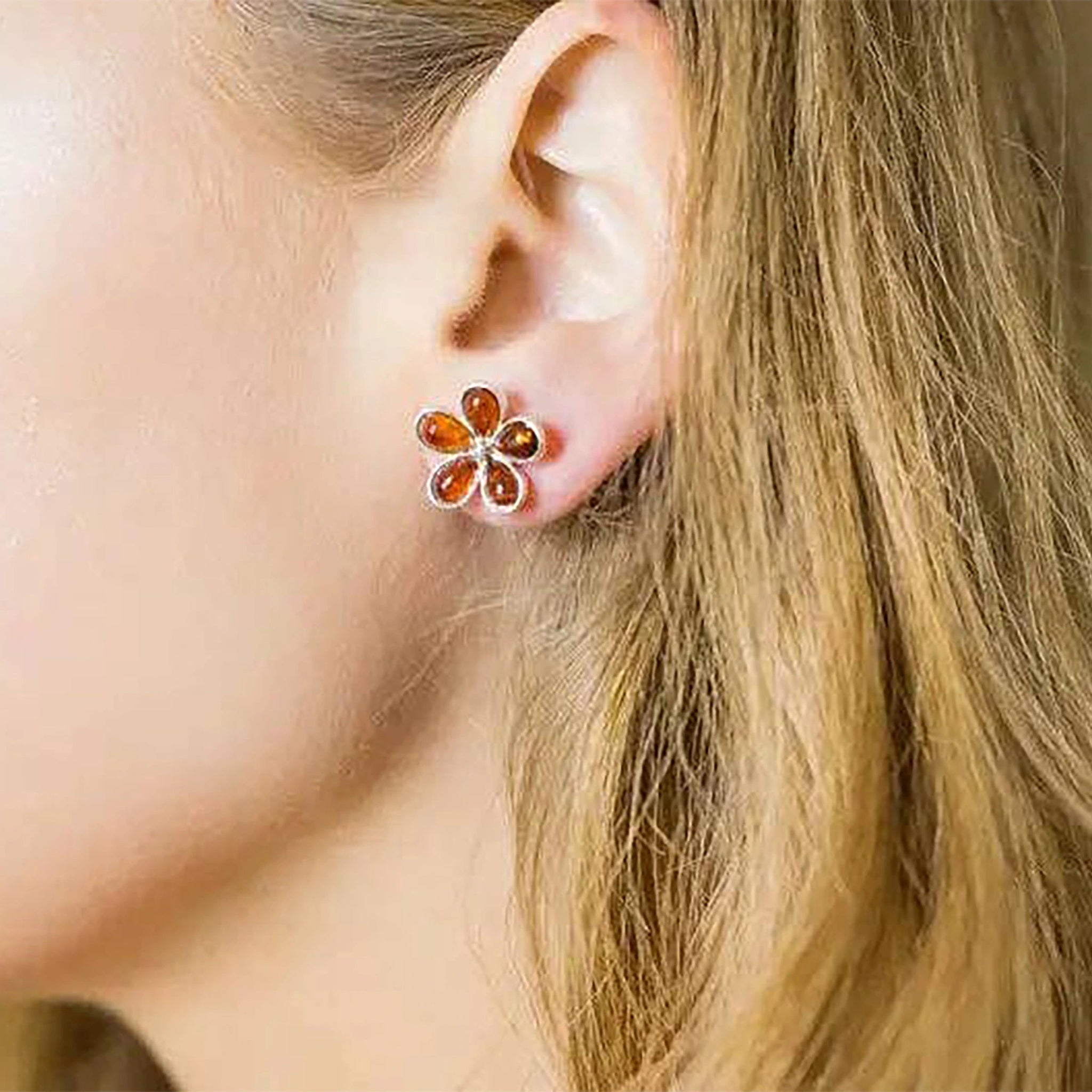 A model is wearing the Baltic Honey Amber Daisy Silver Stud Earrings