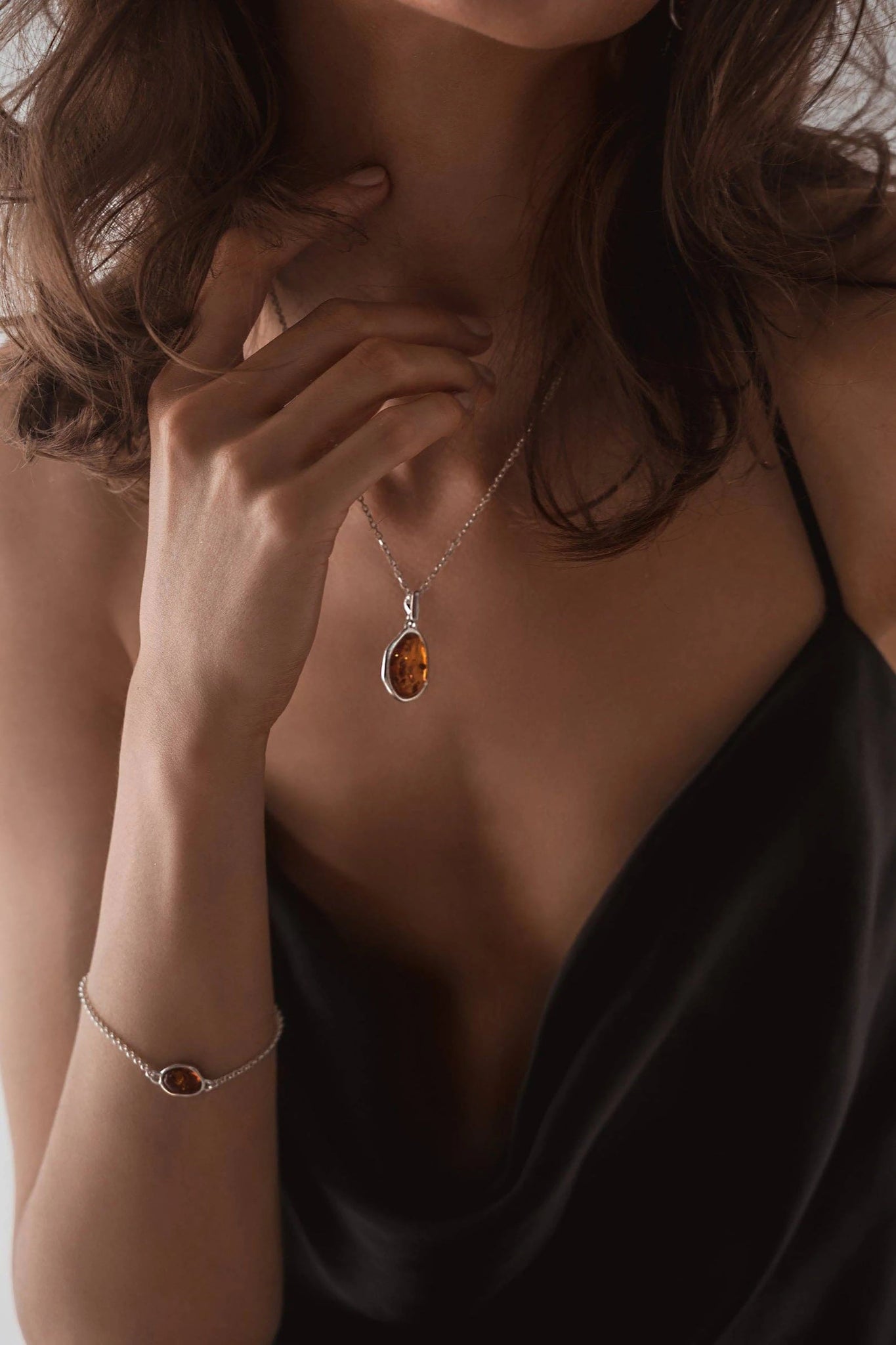 A female model is wearing the Baltic Honey Amber Element Silver Pendant Necklace.