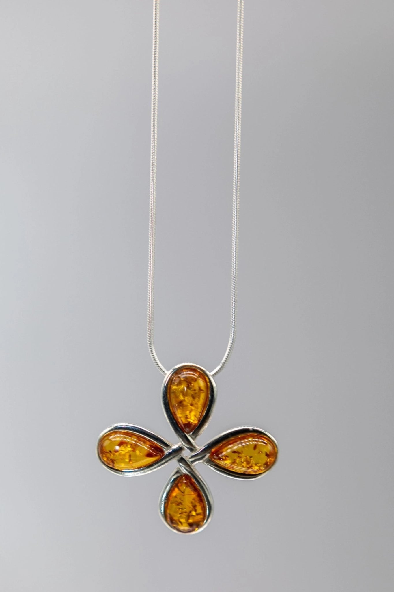 Silver necklace with amber pendant on a gray background