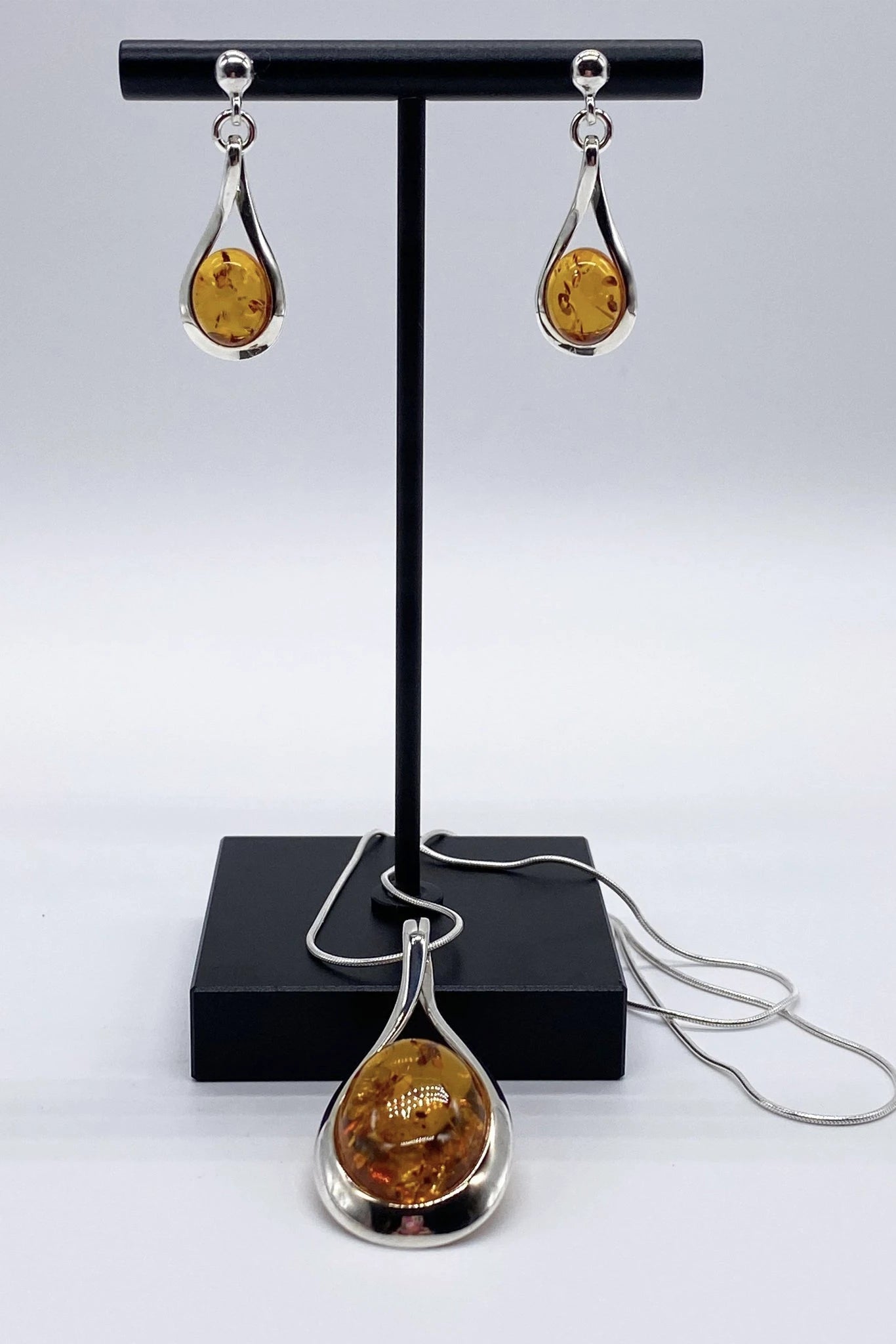 Baltic Honey Amber Sculptured Tear Drop Earrings and necklace on a black jewelry stand - L'Atelier Global