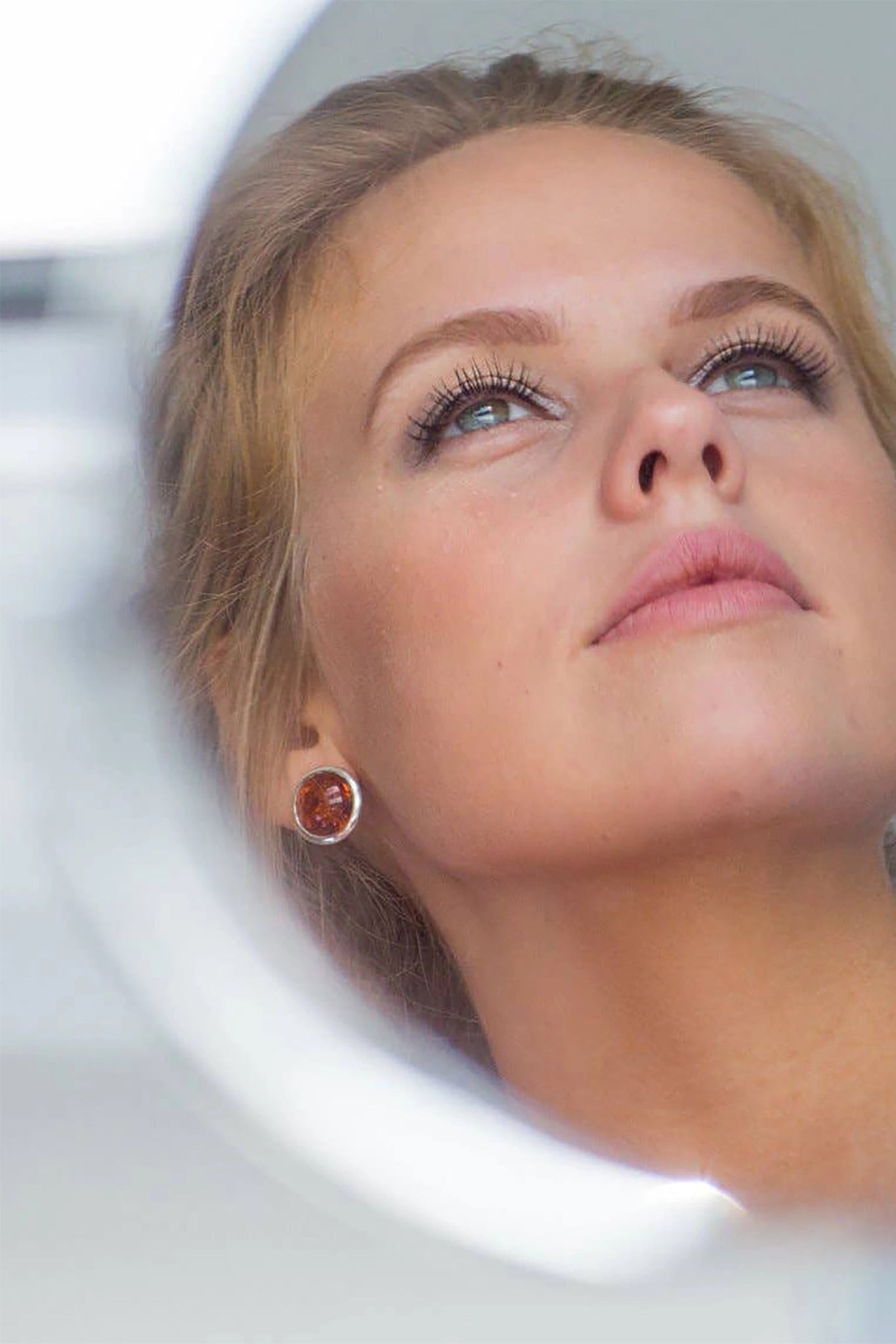 A model is wearing the Baltic Honey Amber Statement Round Stud Earrings