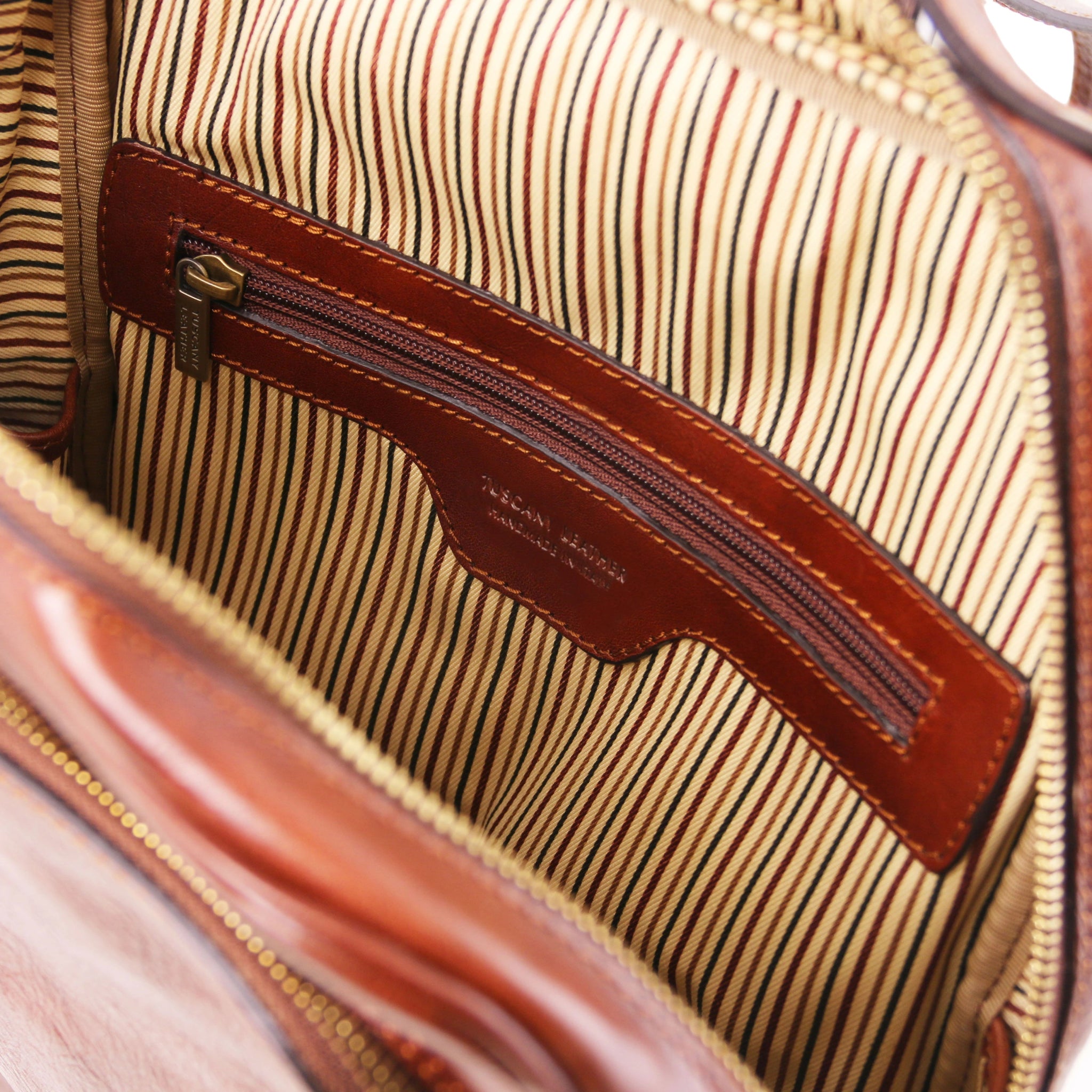 Close-up of a striped interior with zbrown leather zipper pocket and stitching detail.