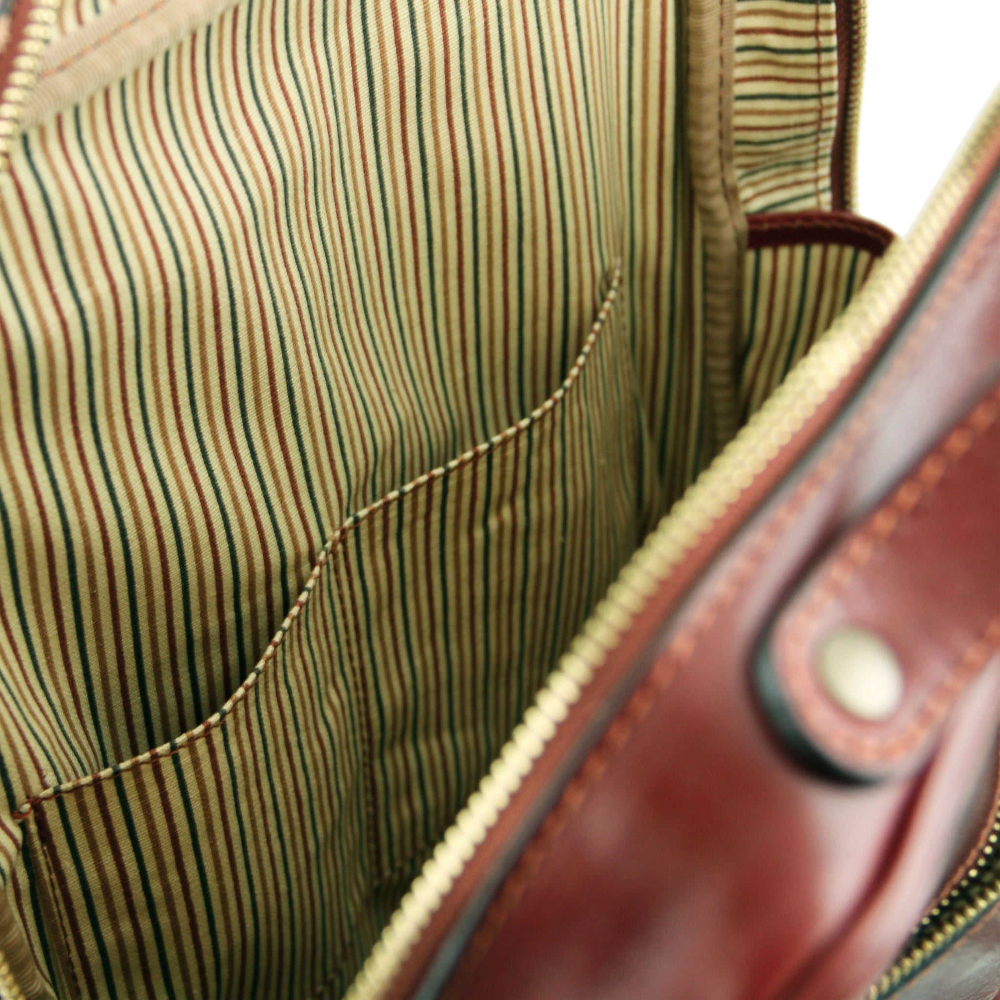 Close-up of a striped fabric interior and opened pockets with a leather handle.
