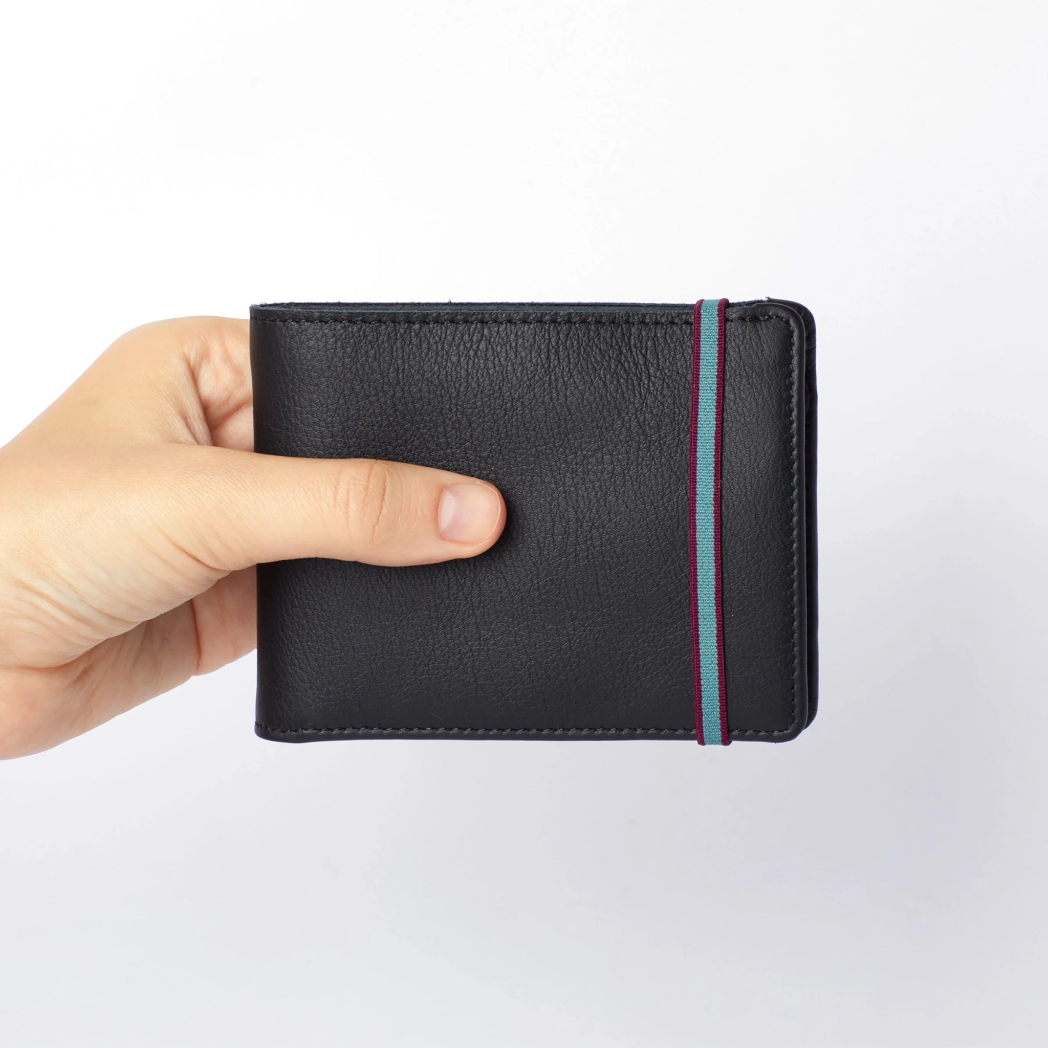 Man's hand holding Black Minimalist Wallet with Coin Pocket with light blue and burgundy trim elastic closure