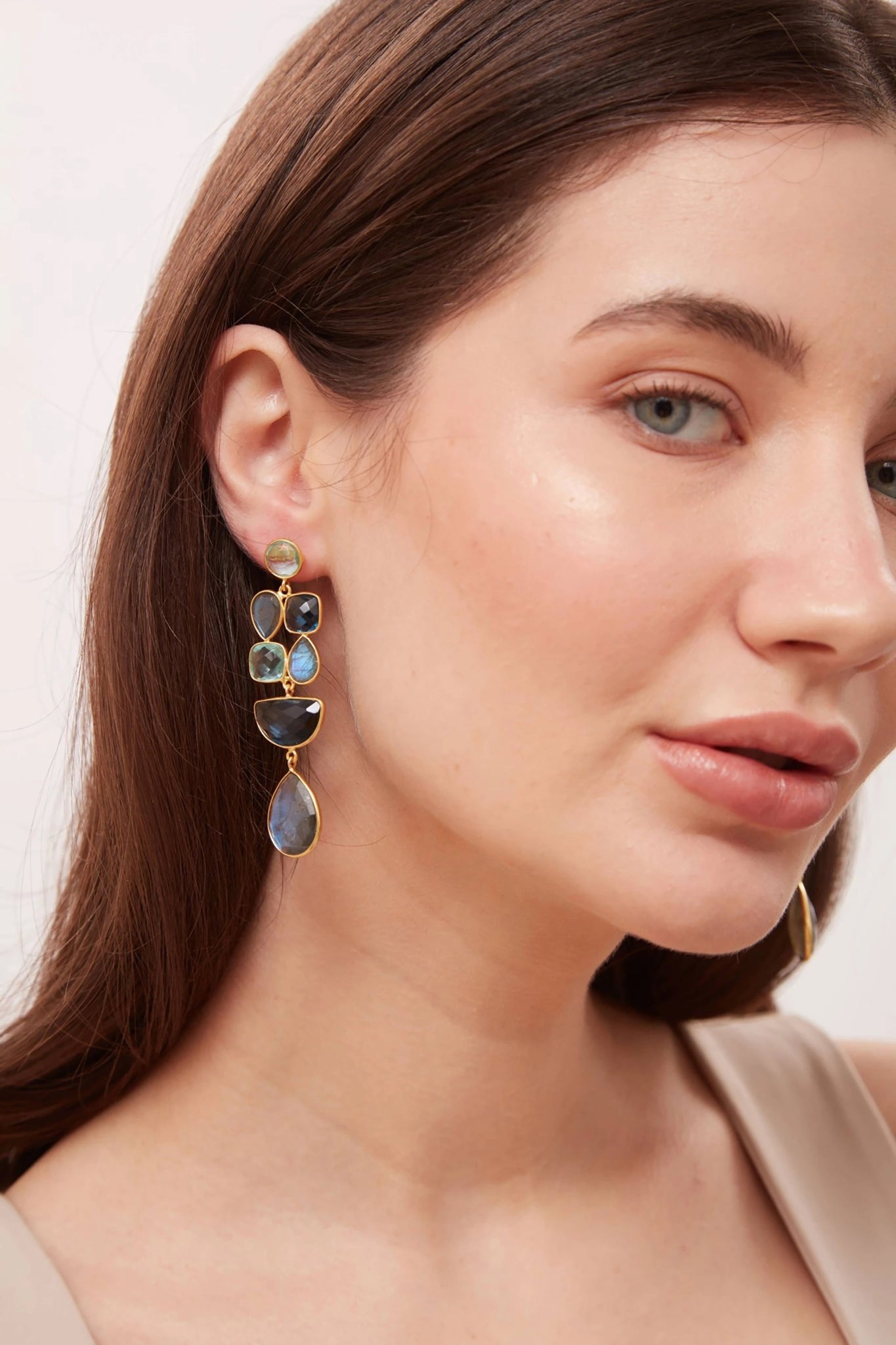 Close-up of a woman wearing a set of earrings with a neutral background