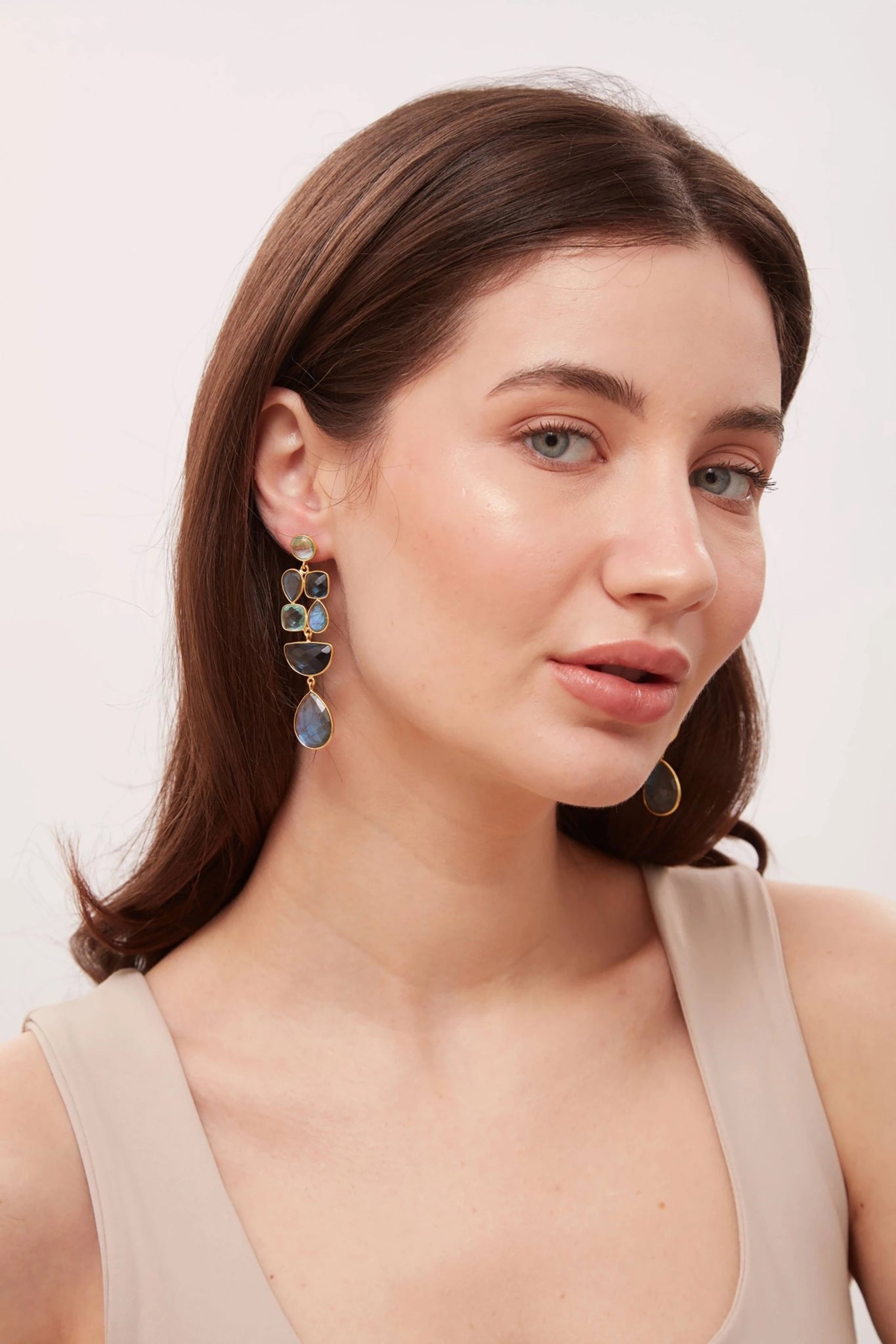Woman wearing a pair of earrings with a neutral background