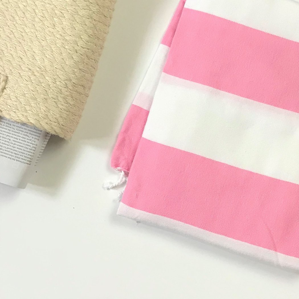 Cabana Turkish Aegean Cotton Towel in pink and white large striped set near a natural woven straw tote bag