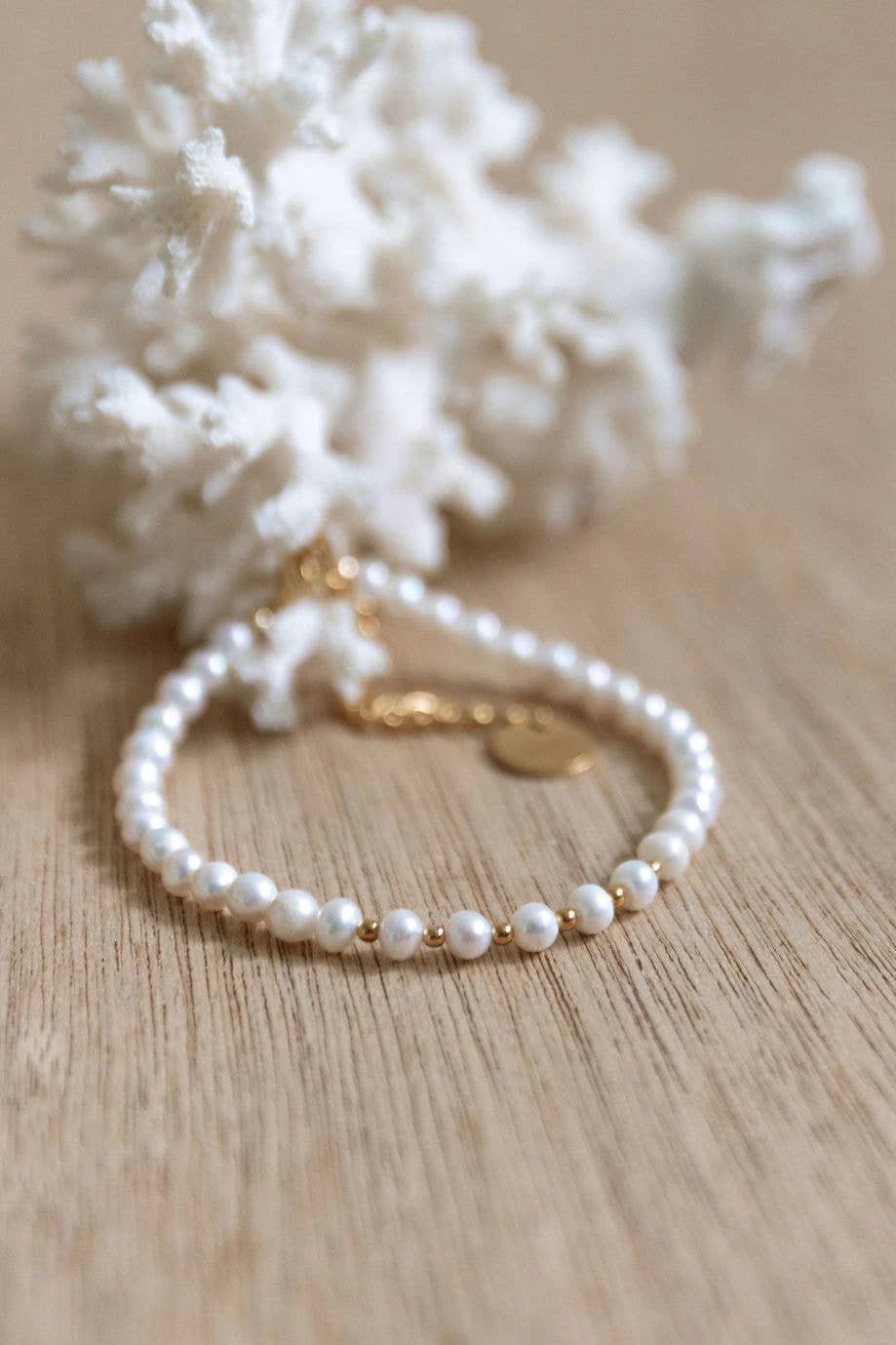 Cassis Golden Pearl Bracelet in gold on natural table next to white sea coral - L'Atelier Global