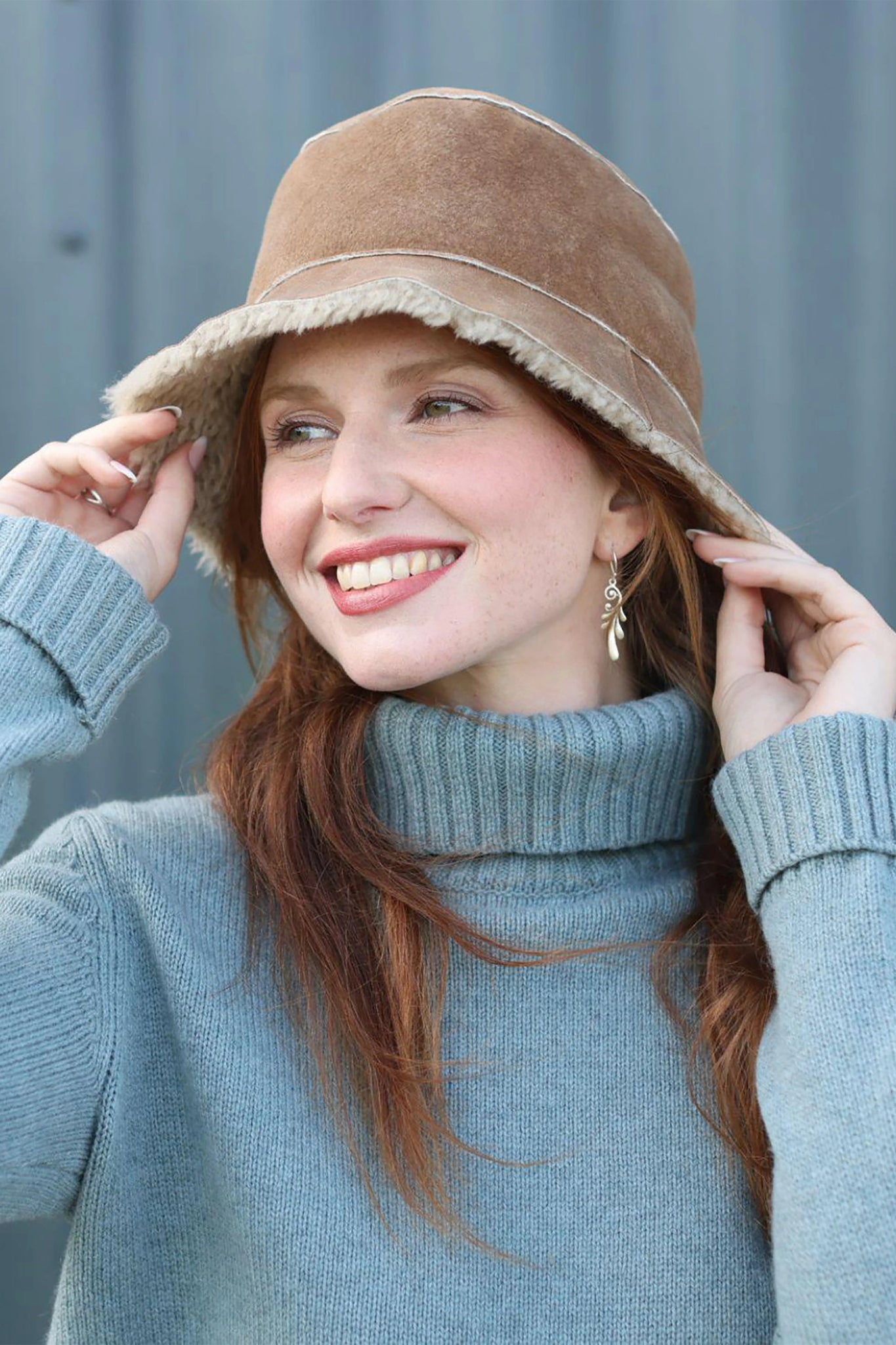 Front side view English Sheepskin Bucket Hat in Tan Gonfio on a model wearing a light blue turtleneck sweater