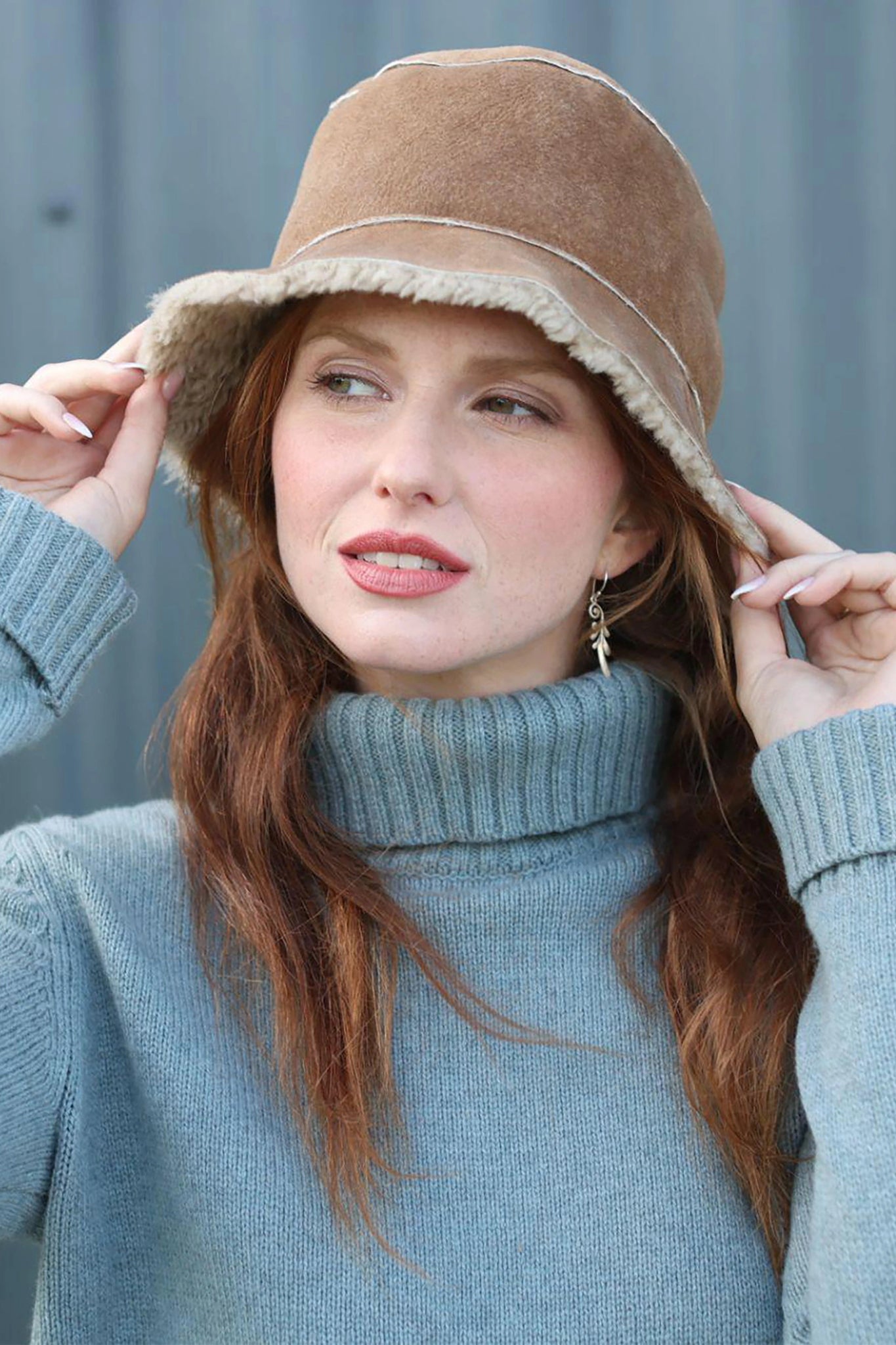 Front view English Sheepskin Bucket Hat in Tan Gonfio on a model wearing a light blue turtleneck sweater