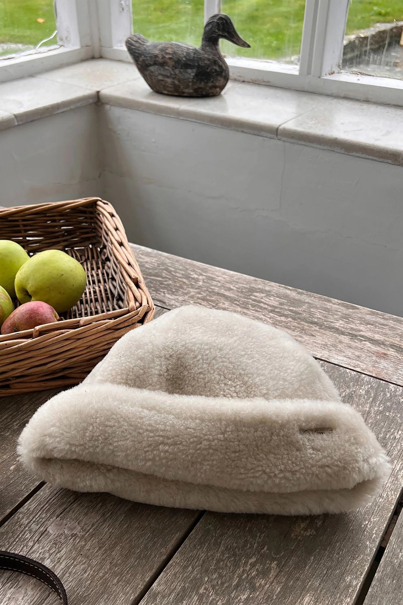 English Sheepskin Pull On Beanie in Cream laying on a kitchen table
