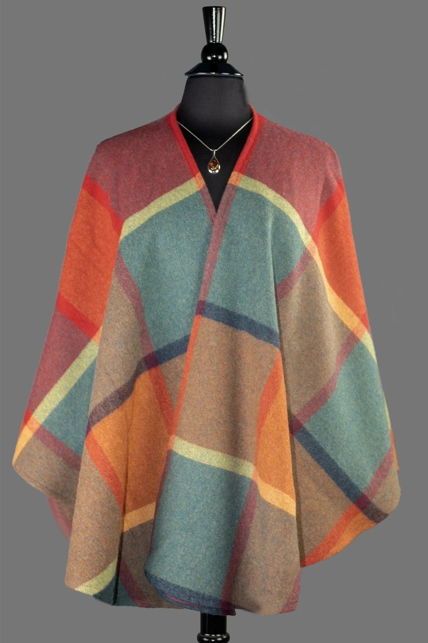 Multicolored poncho on a mannequin against a gray background