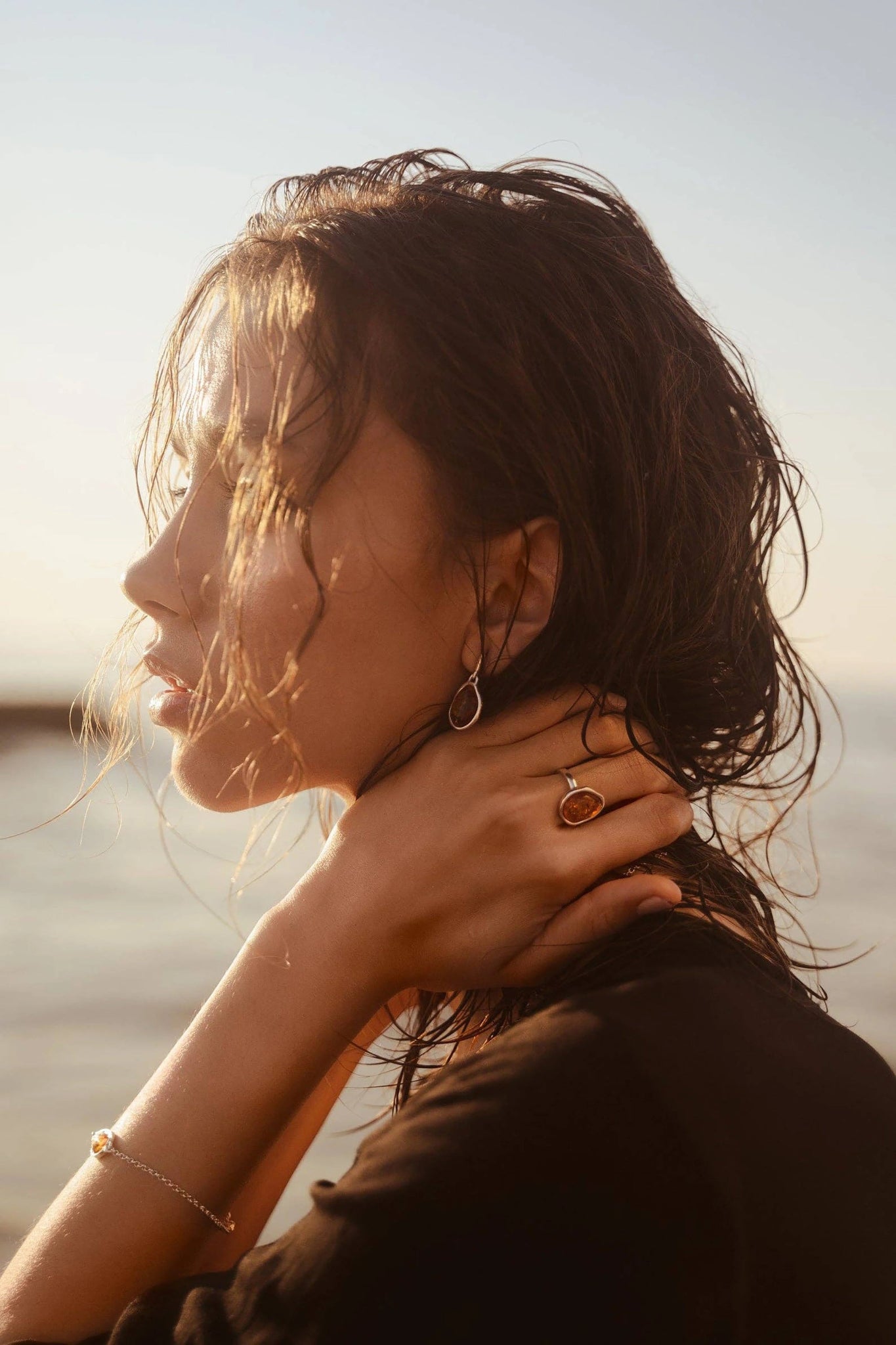 A female model's is wearing the Honey Baltic Amber Element Solitaire Adjustable Ring and Drop Earrings