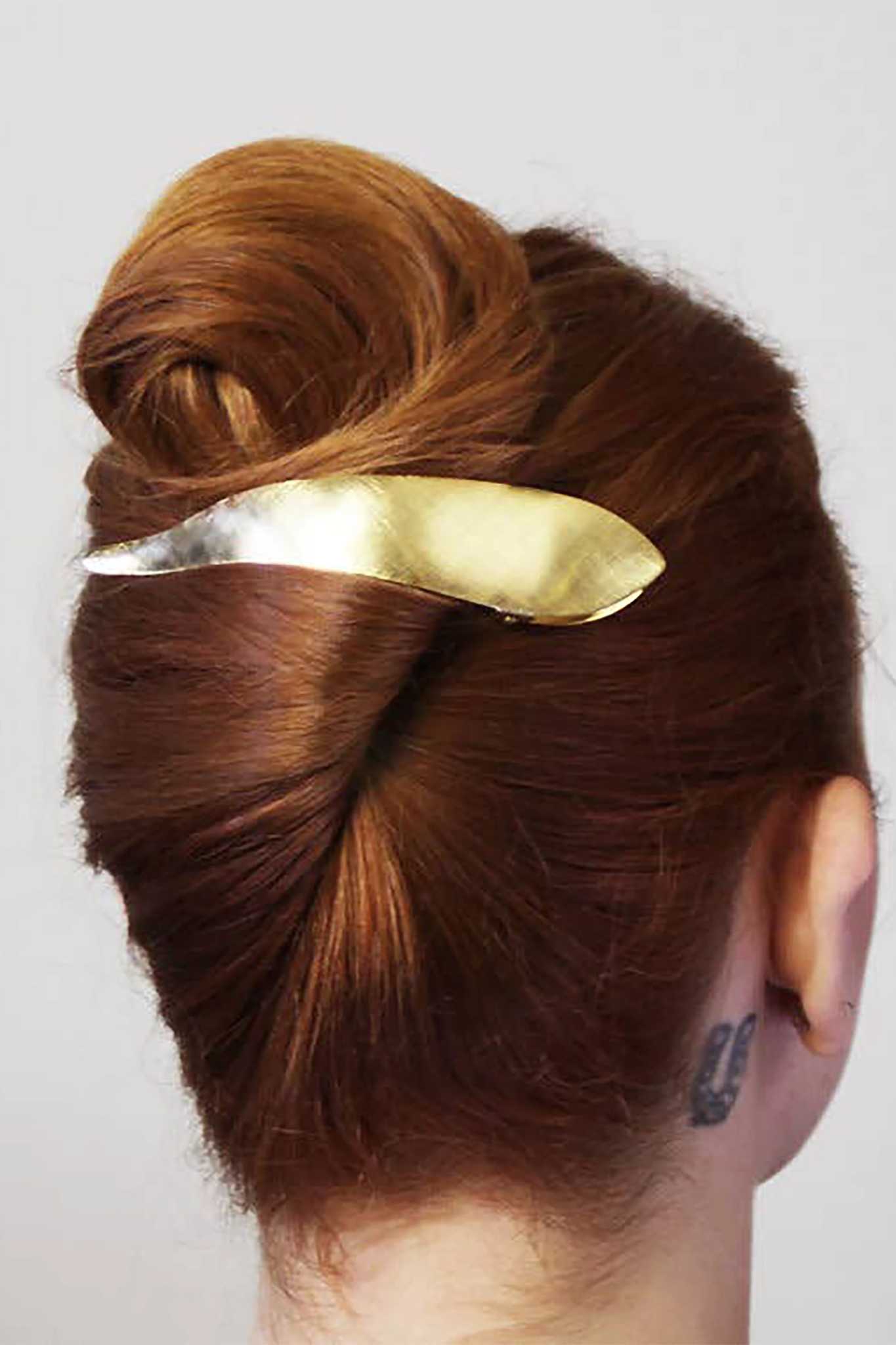 Ice Gold hair clip in a red hair bun with a plain background