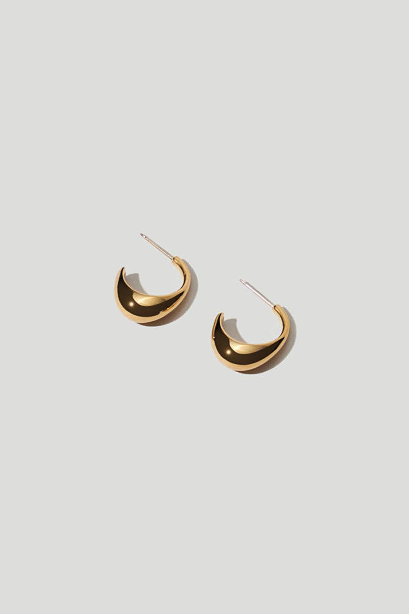 Inez Gold Hoop Earrings laying o a white background.