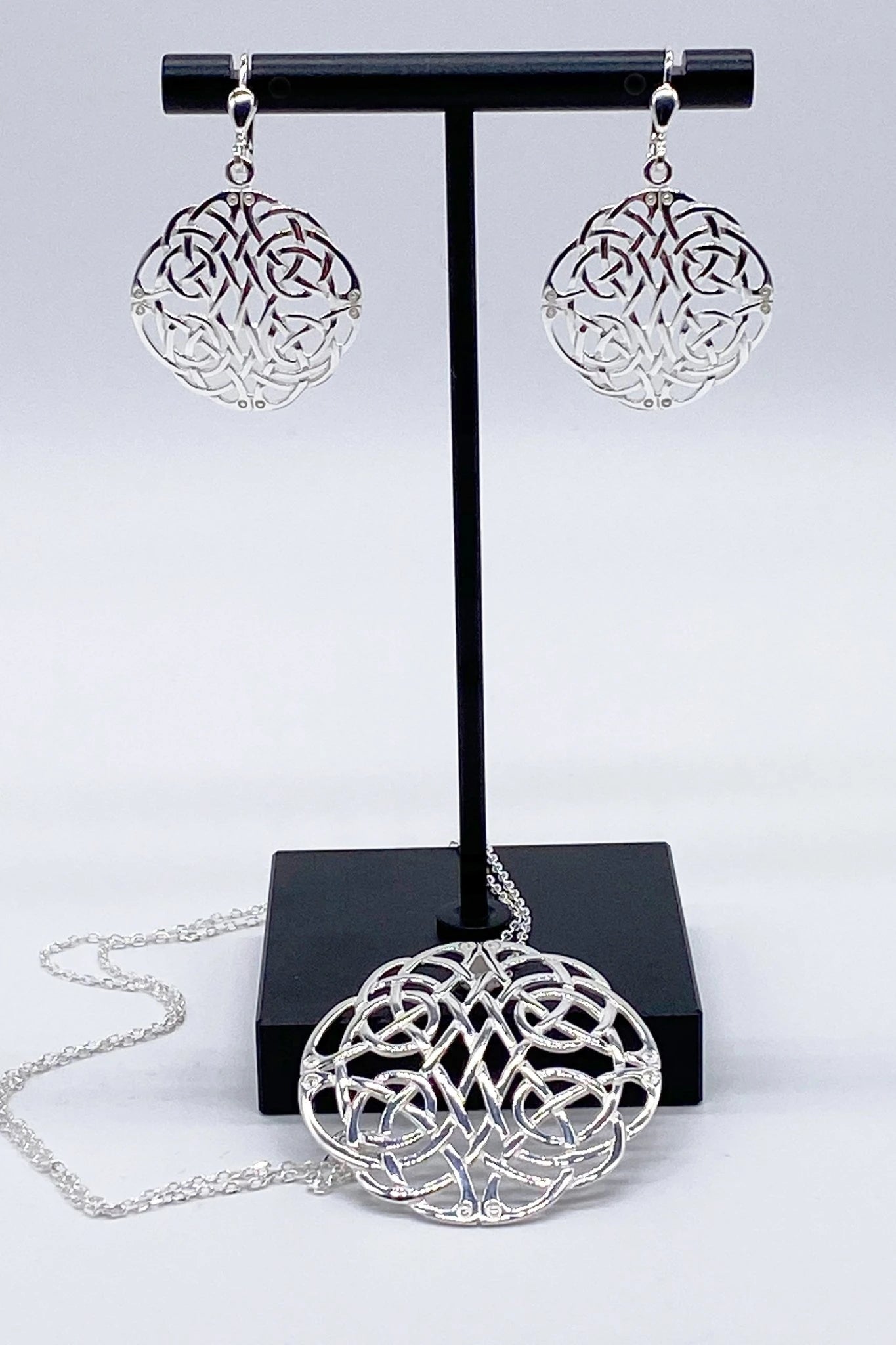 Irish Celtic Woven Knot Sterling Silver Necklace and earrings on a black jewelry stand - L'Atelier Global