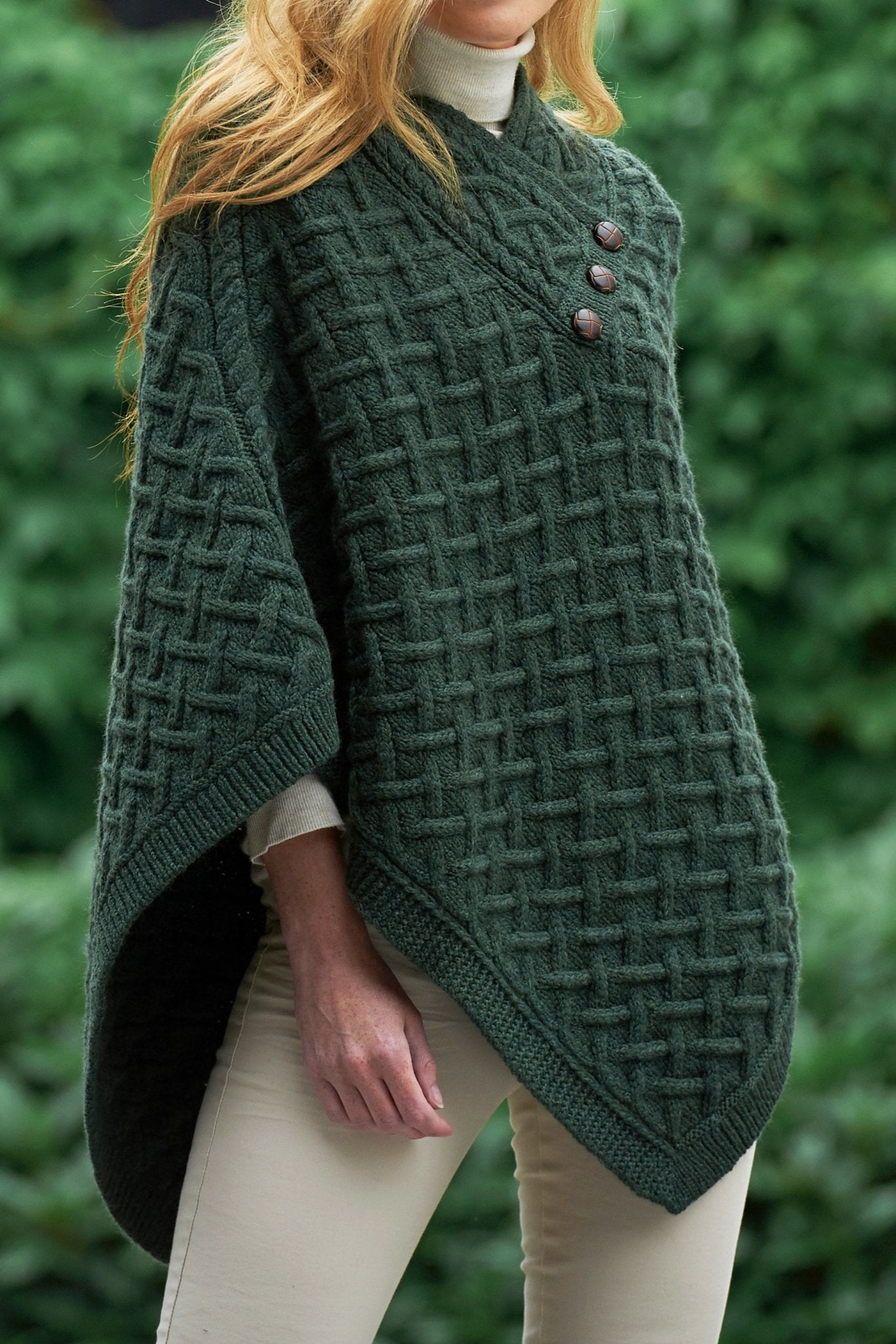 Irish Connemara Supersoft Merino Wool Poncho in green on a model. Three fixed buttons are showcased on the chest