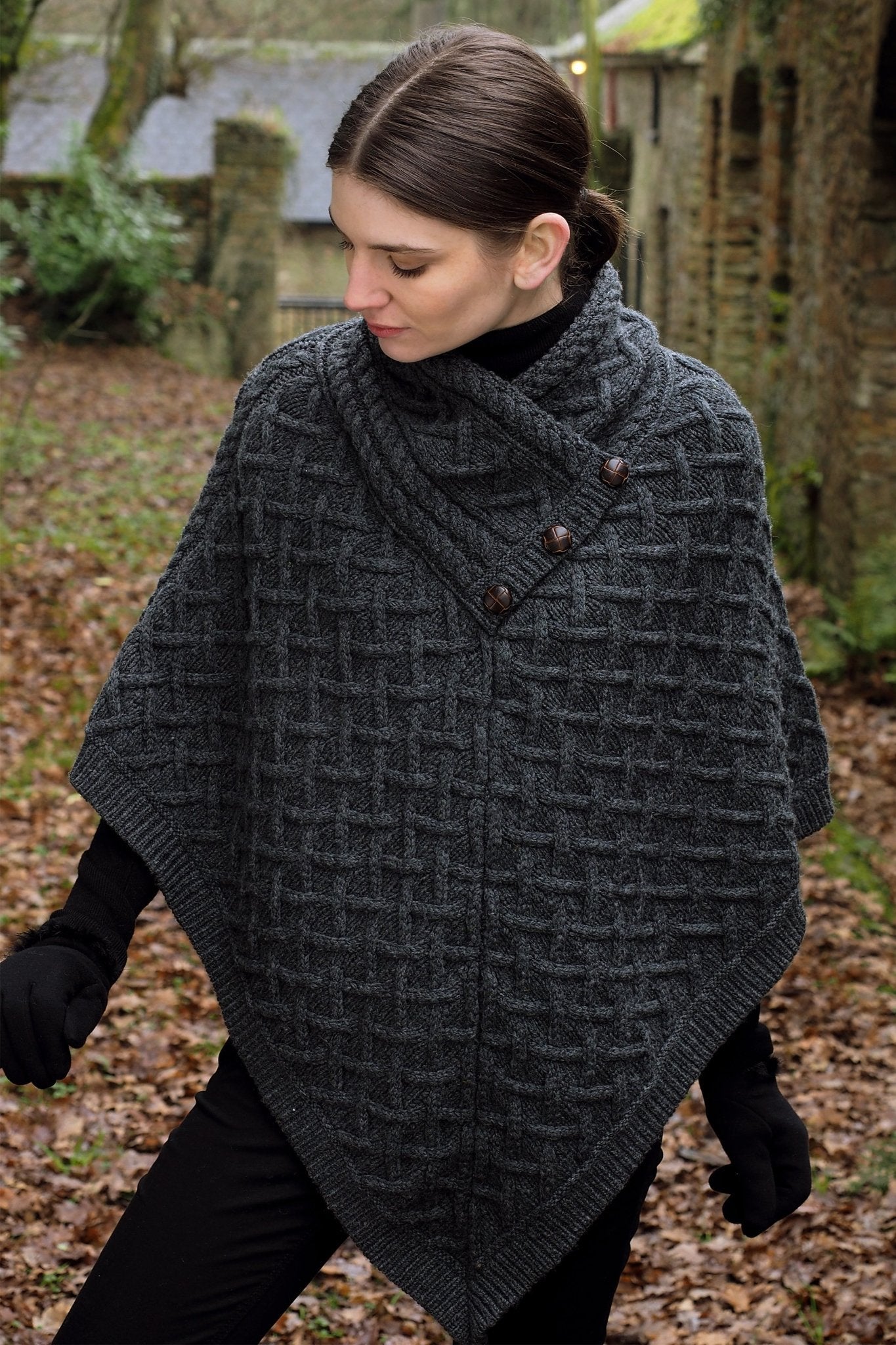 Irish Connemara Supersoft Merino Wool Poncho in charcoal on a model. Three fixed buttons are showcased on the chest